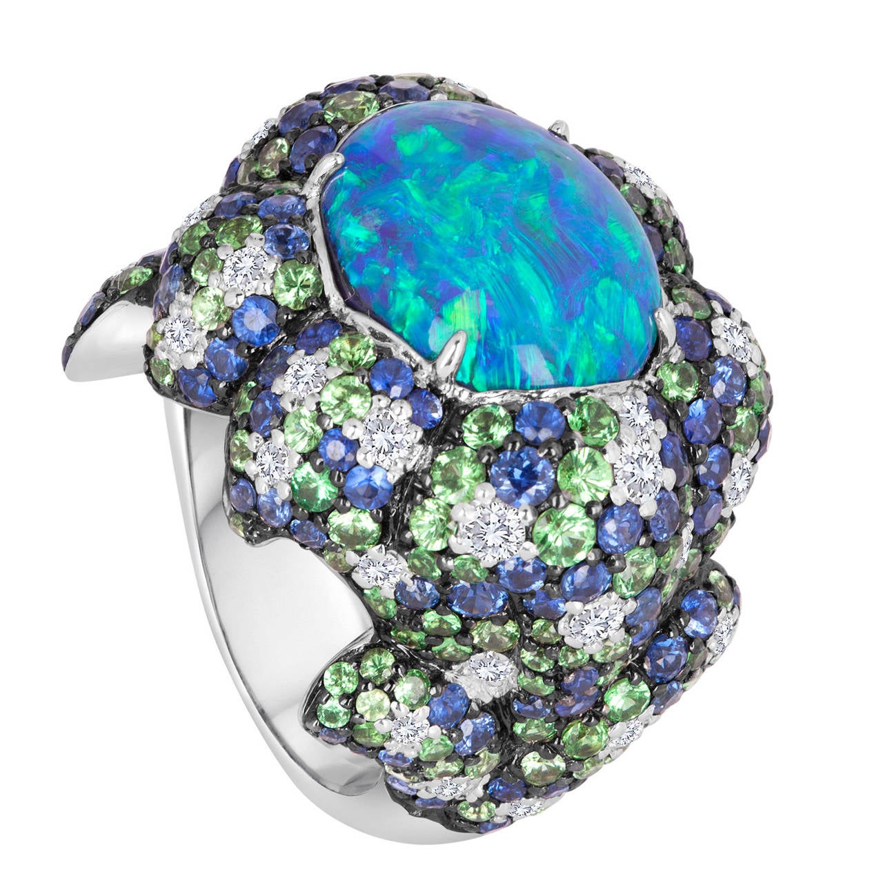 This one-of-a-kind design features an Australian black opal that presents us with deep colors of blue and green. The center stone is prong-set in an 18k white gold setting that is studded with a variety of precious gemstones that include diamonds,