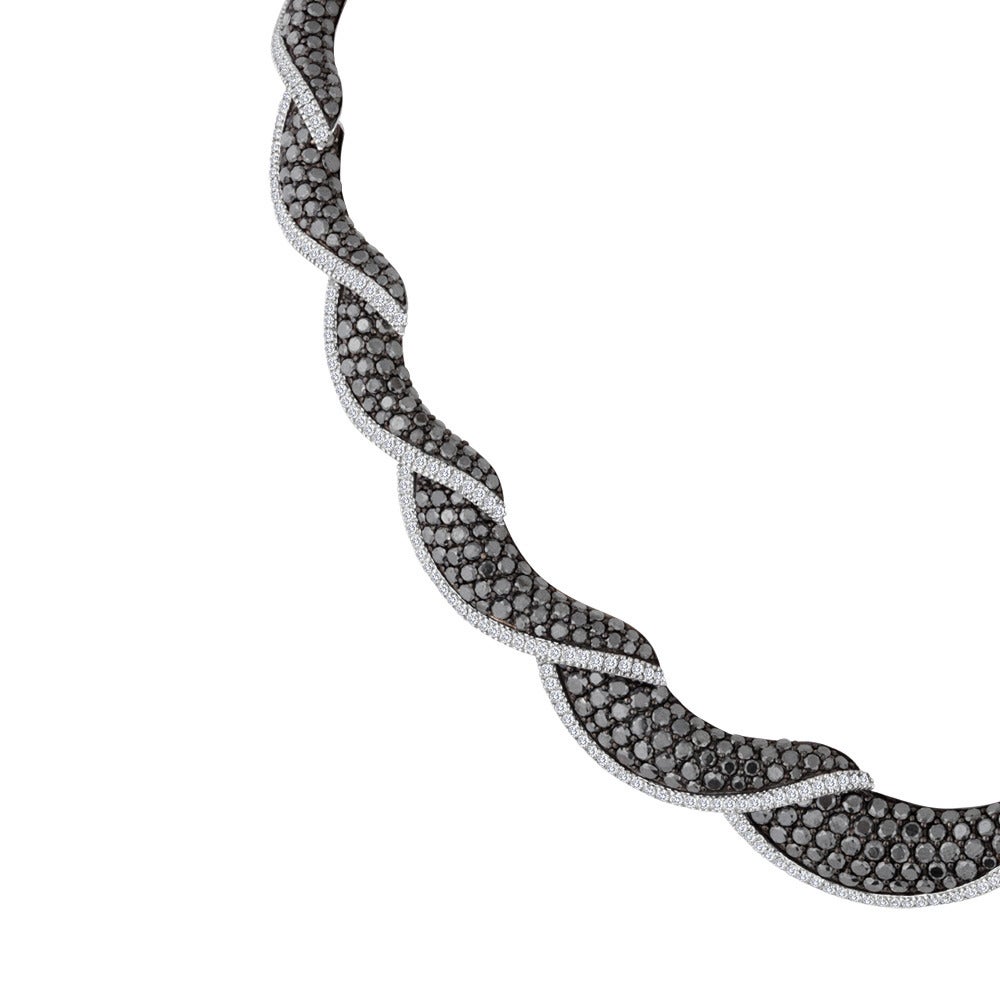 This creative design features a series of links that contain black diamonds, lined with a single row of white diamonds. Together, they create a twist pattern across the neck. The diamonds are set in 18k white gold. The total weight of black diamonds