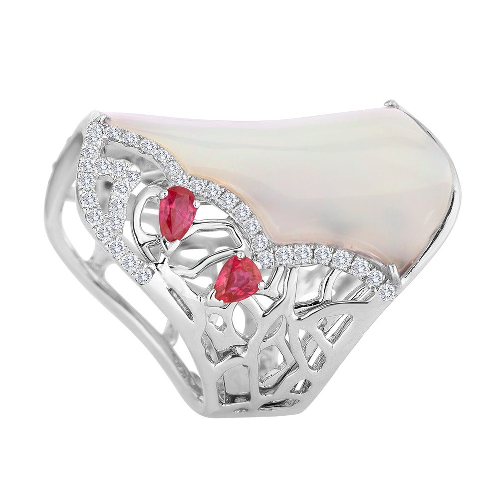 This ring was inspired by the mother of pearl that ended up in our graces. From its unique curvature, we designed a ring that would accommodate it. Sprinkled around the main piece to accent it are several pear shape rubies. All are set in an 18k