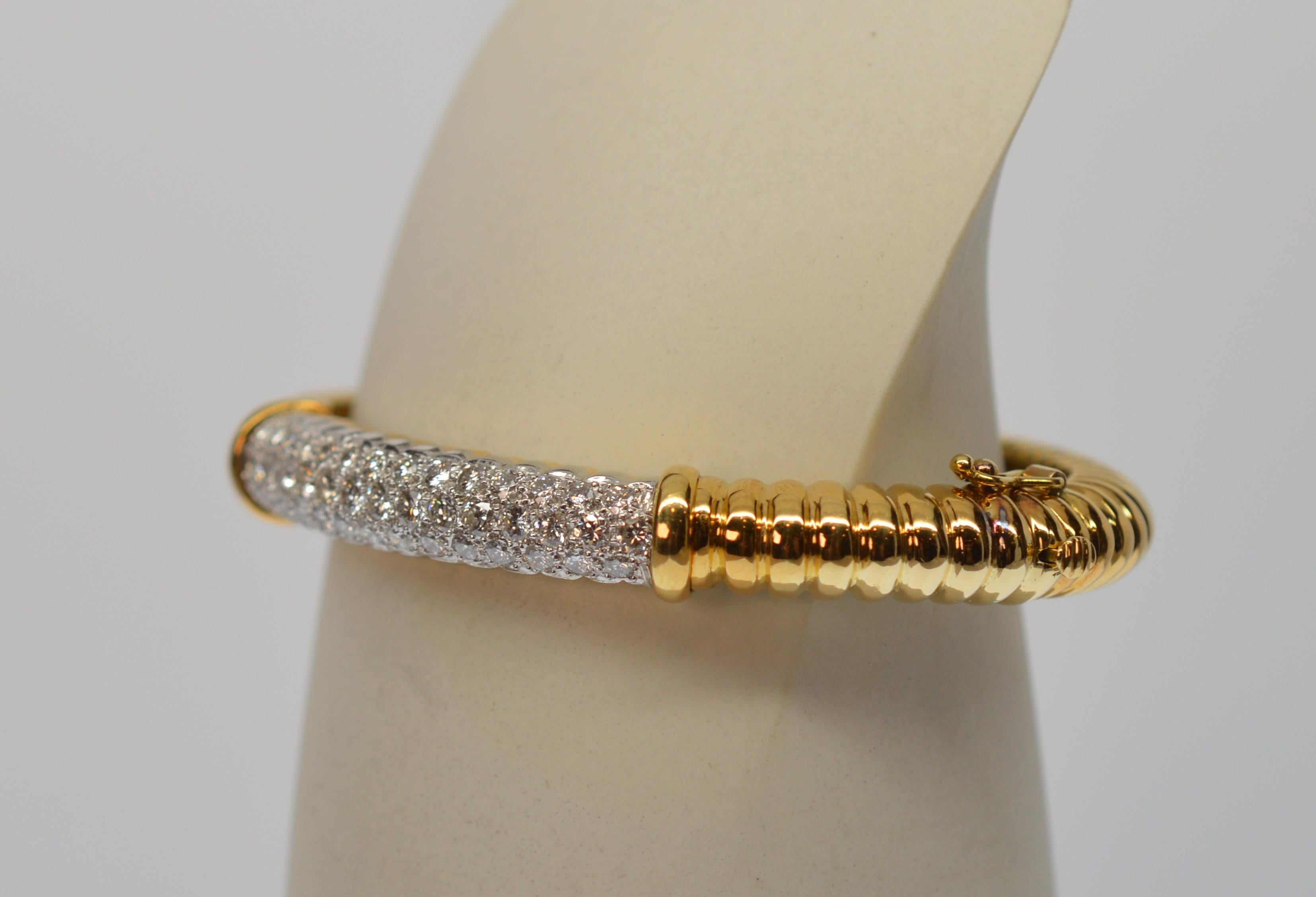 Impressive, finely constructed eighteen karat yellow gold bangle bracelet is stunning with well over an inch of bright white diamond inlaid across the front placket . The band, measuring 2-1/4 x 1-3/4 inches inside, is a rope design that creates