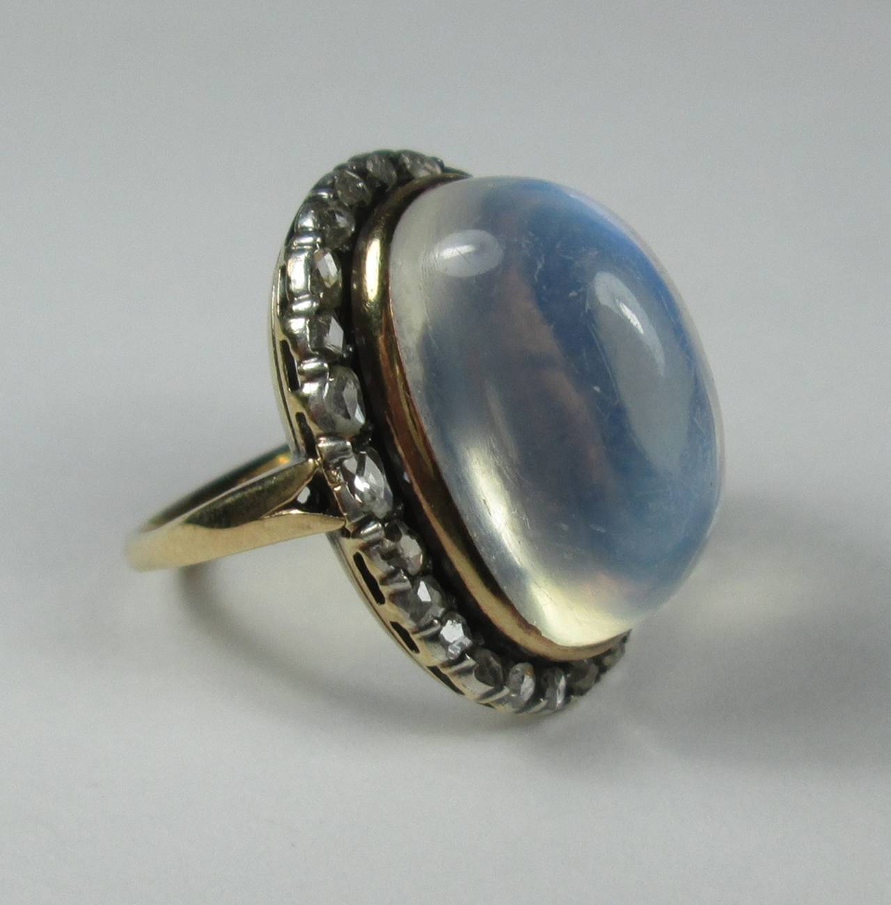 The central oval moonstone cabochon with a nice blue adularescence, to a silver topped diamond cluster surround.

Mounted in yellow gold

Finger size: 7 

Weight: 8.4 gr

PLEASE NOTE: OUR PRICE IS FULLY INCLUSIVE OF SHIPPING, IMPORTATION