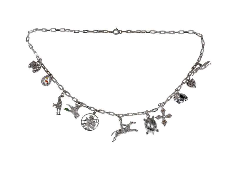 Collana con ciondoli incastonati, con catena in oro bianco 18 carati, che sostiene undici ciondoli, ognuno dei quali raffigura un soggetto diverso, tra cui una volpe, un cane, una tartaruga, una croce, un cavallo, un fagiano, un uccello, uno jockei