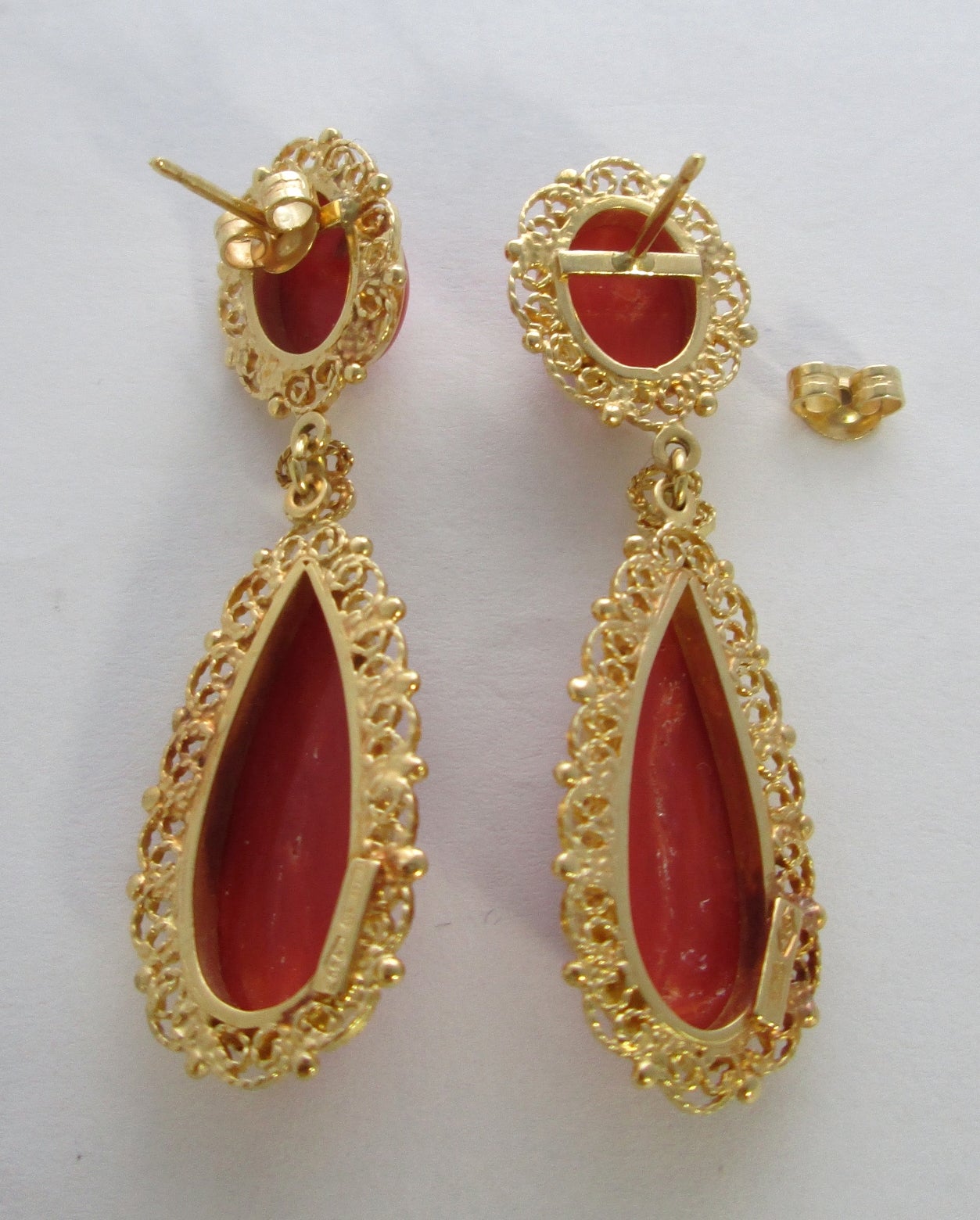 The oval gold tops centering 2 oval smooth cabochon coral approx. 10 mm high, suspending 2 pear shaped corals of similar pattern approx. 22 x 8 mm, each earring with ornate filigree decorations

Mounted in 18Kt yellow gold

Posts and butterfly