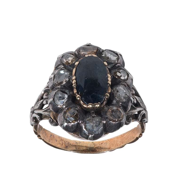 The bezel shaped as a hinged cluster set with an oval cut sapphire and rose cut diamond revealing a small secret compartment, to a foliate trifurcated shoulders, mounted in silver and gold.

Circa 1800

Finger size: 7

Weight: 8.1 gr

PLEASE