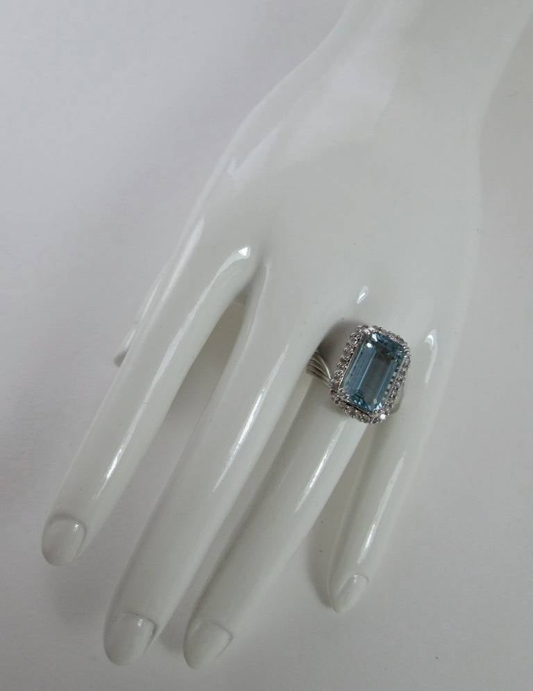 The step cut aquamarine weighs approximately 10 carats, claw set within a border of round cut diamonds to a contrarie-shaped hoop. Mounted in 18Kt white gold.

Finger size: 7
Weight: 10.6 gr

PLEASE NOTE: OUR PRICE IS FULLY INCLUSIVE OF