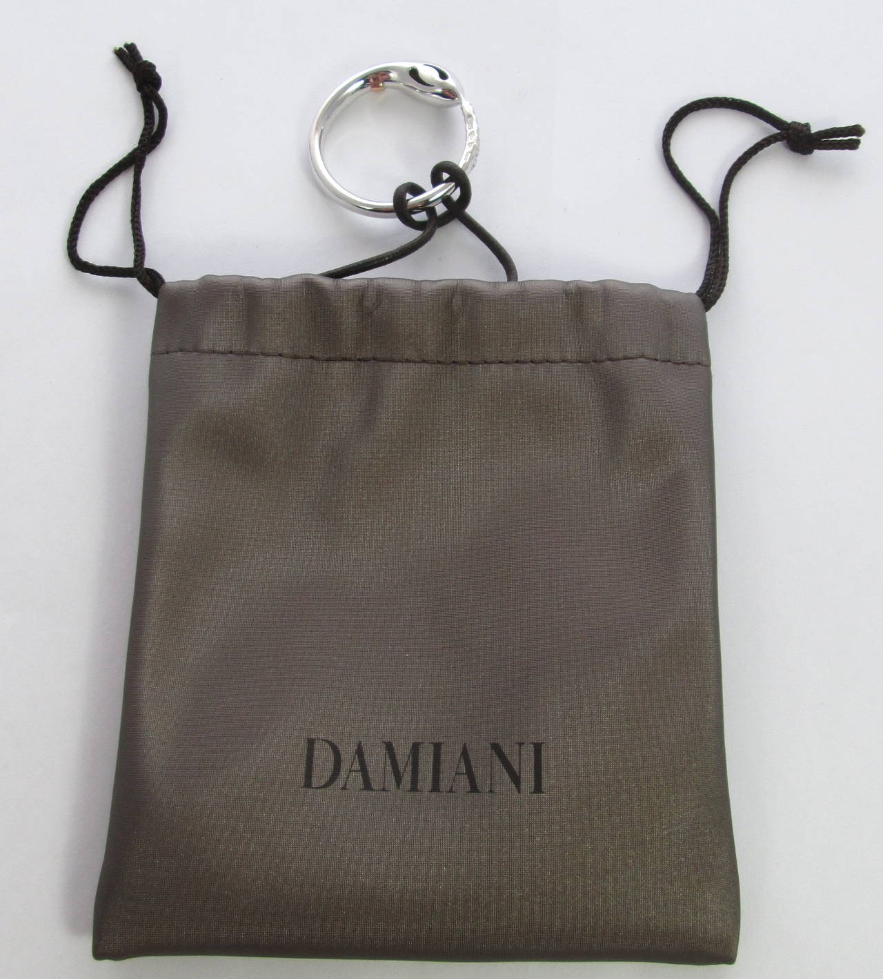 The Damiani necklace composed by black cord with white gold pendant attached, partly set with diamonds and a with a small rose gold band.
Mounted in 18Kt White and rose gold
Fully marked and signed Damiani
Diamond Carat Weight: 0.15

Weight: 11.1