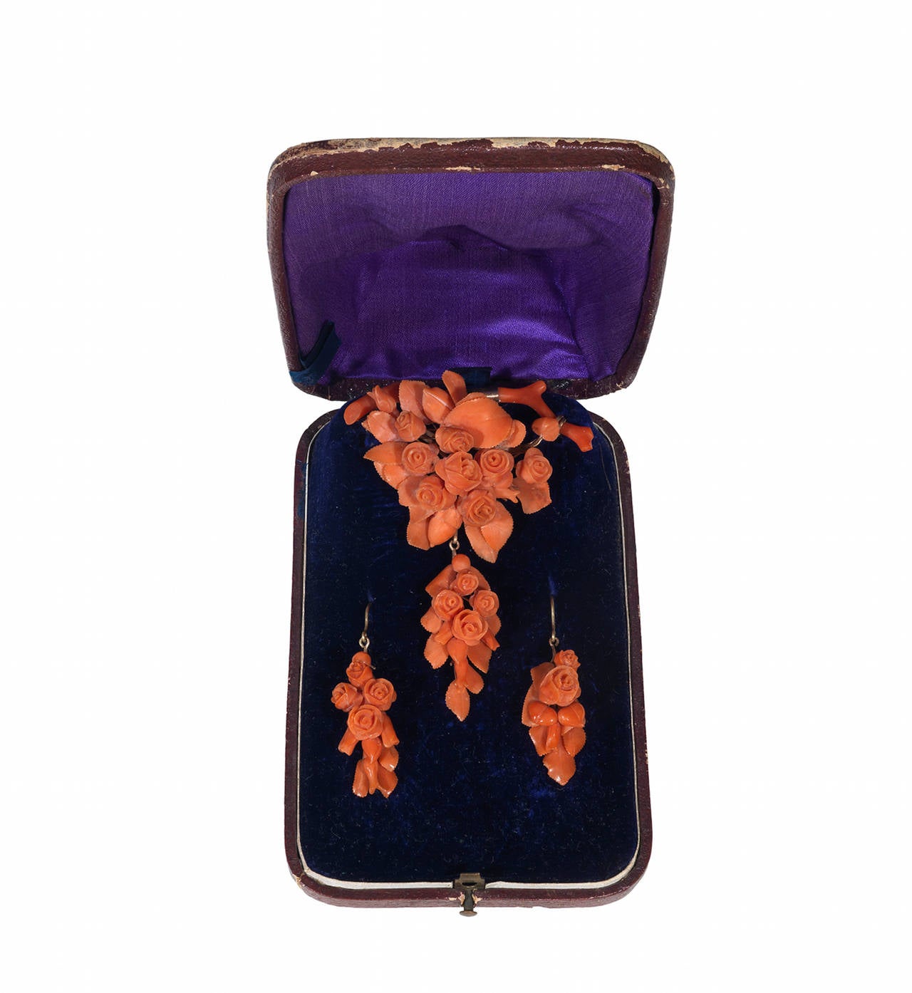 The brooch formed as a series of corals carved as flowers and leaves, the earrings of complimentary design, to hook fittings, brooch width 59mm and length 81mm, earring length 41mm, to a fitted case.