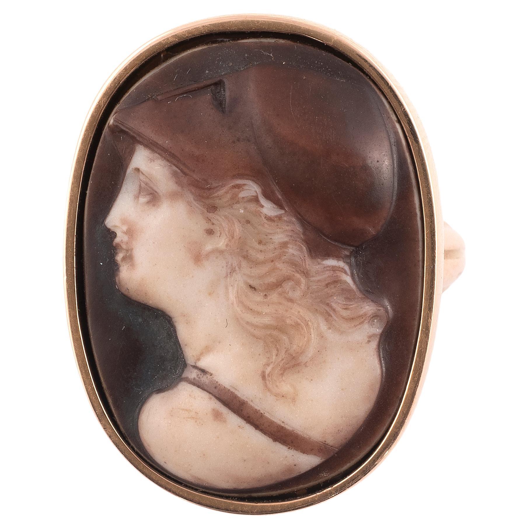 

The oval stained agate cameo carved to depict the goddess Athena in her crested helmet.
Cameo lenght 28mm
18kt gold mounted, size 7
The Ancient Greek goddess Athena/Athene, known as Minerva by the Romans, was the goddess of war, but also of wisdom.