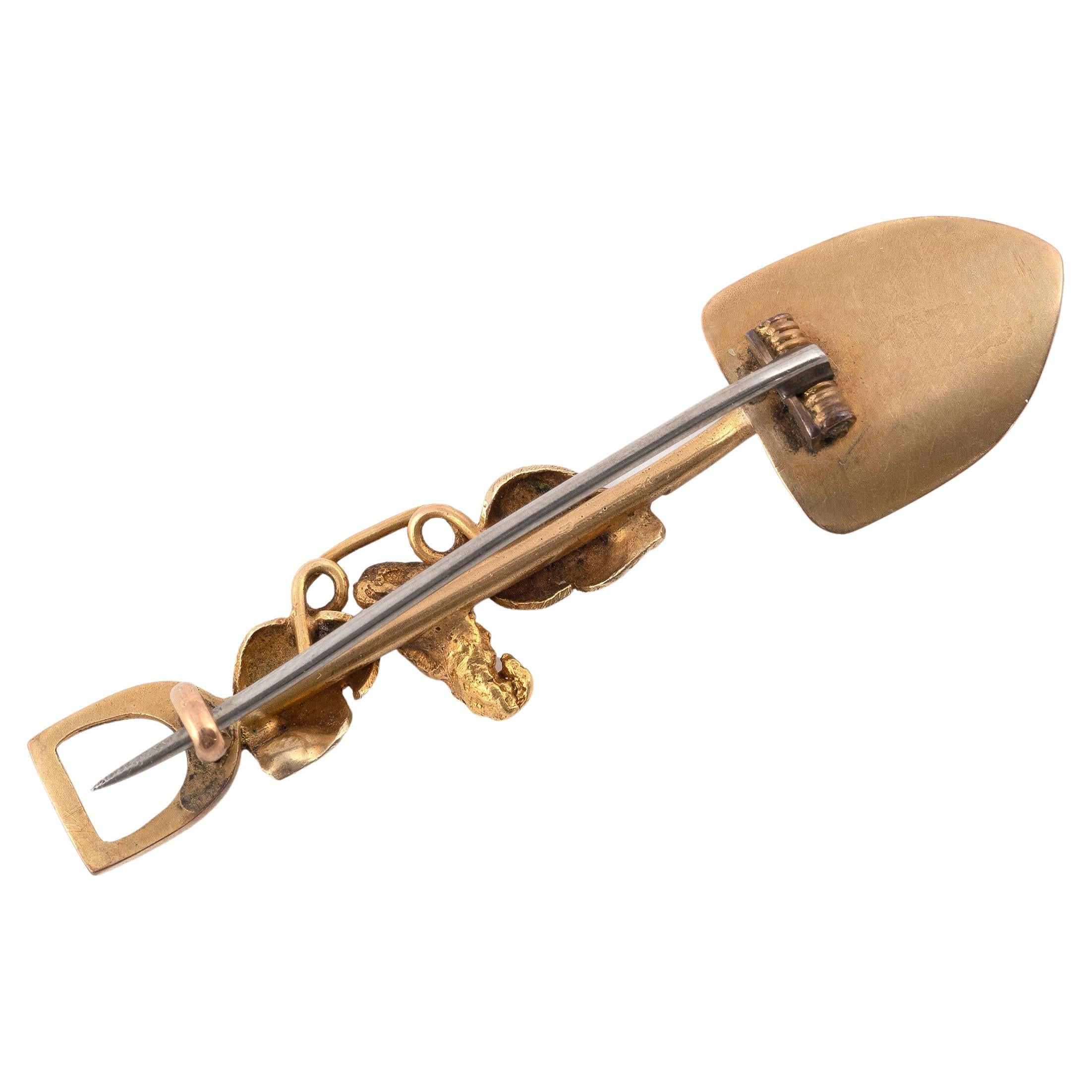 
Composed of a shovel, pick axe and nugget, and a late Victorian gold bar brooch, brooch length 5.4cm. 


