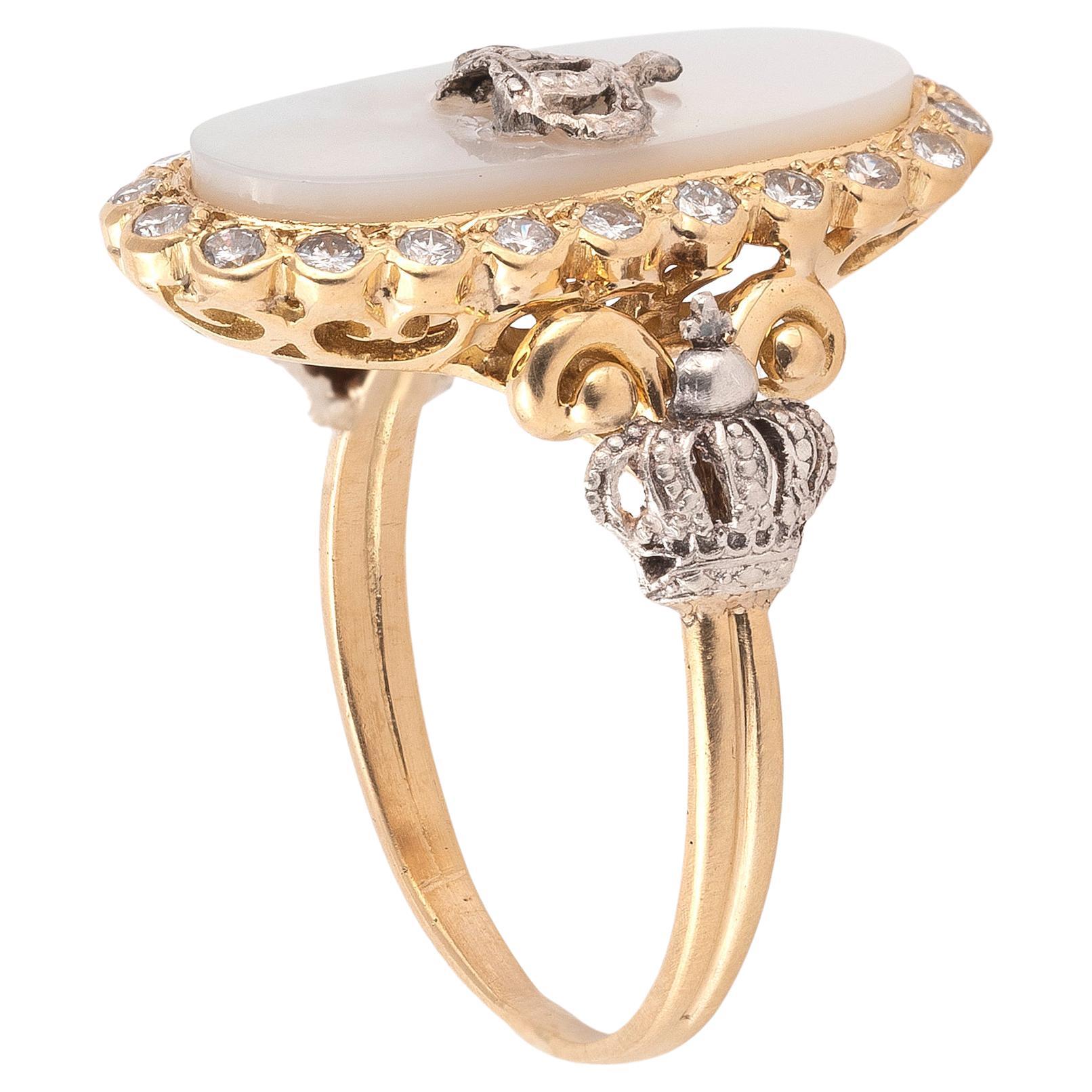 

Yellow gold ring, adorned with an oval MOP plaque set with a royal silver crown surrounded by brilliant cut diamonds. The frame uses the motifs of crowns. Ring size: 7 1/2. 
Weight: 6.3g 