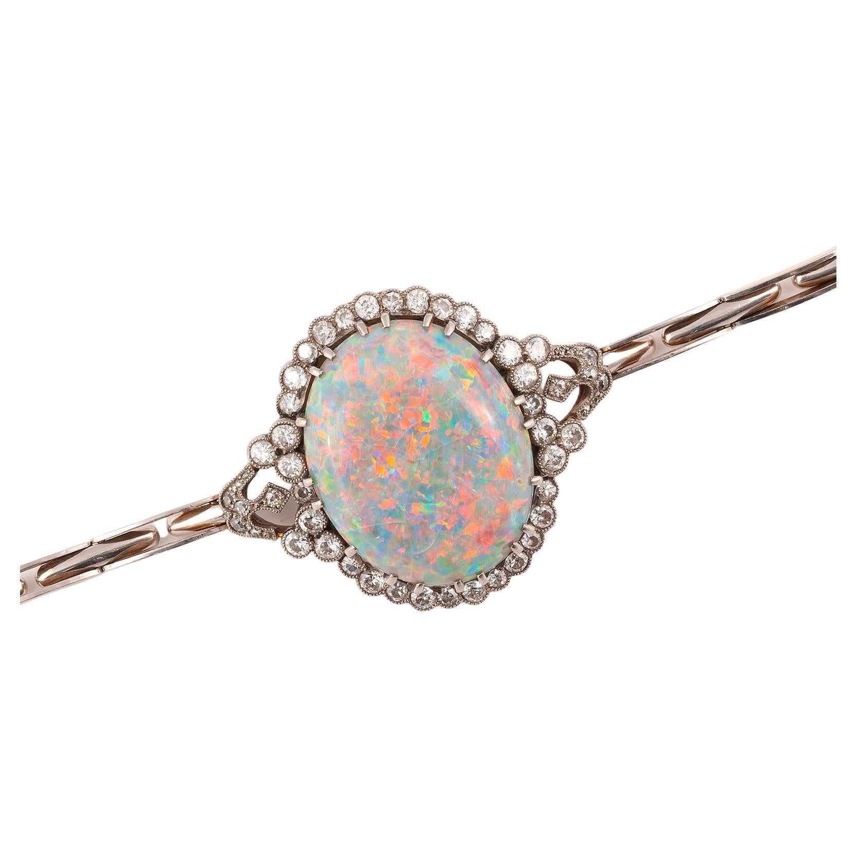Ein wichtiges ovales Armband aus Opal, Diamant und Gold, das sich in einen Anhänger verwandeln lässt, um 1910. 
Ovaler Cabochon-Opal, ca. 30 mm x 28 mm; geschätztes Gesamtgewicht: 20cts; 
Bruttogewicht : 23,26 gr. 
Oberer Armreif : 3,2x 3 cm. 
Länge