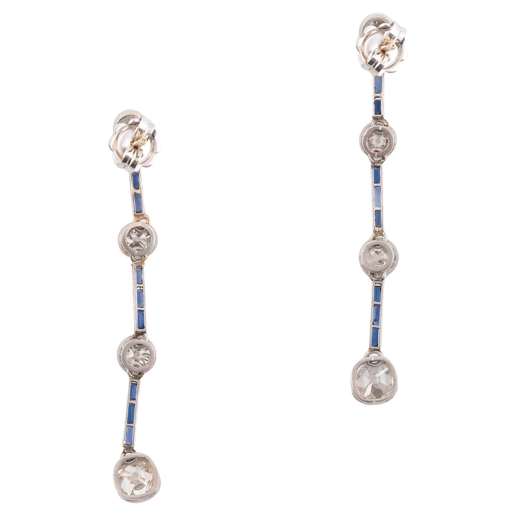 Each designed as an hanging row of four millegrain set old cut diamonds, the eight stones weighing overall approximately 3.50 cts, interspaced by collet set calibre cut sapphire.

Screw lock on the back.

Mounted in platinum.

Length: 5 cm

Weight: