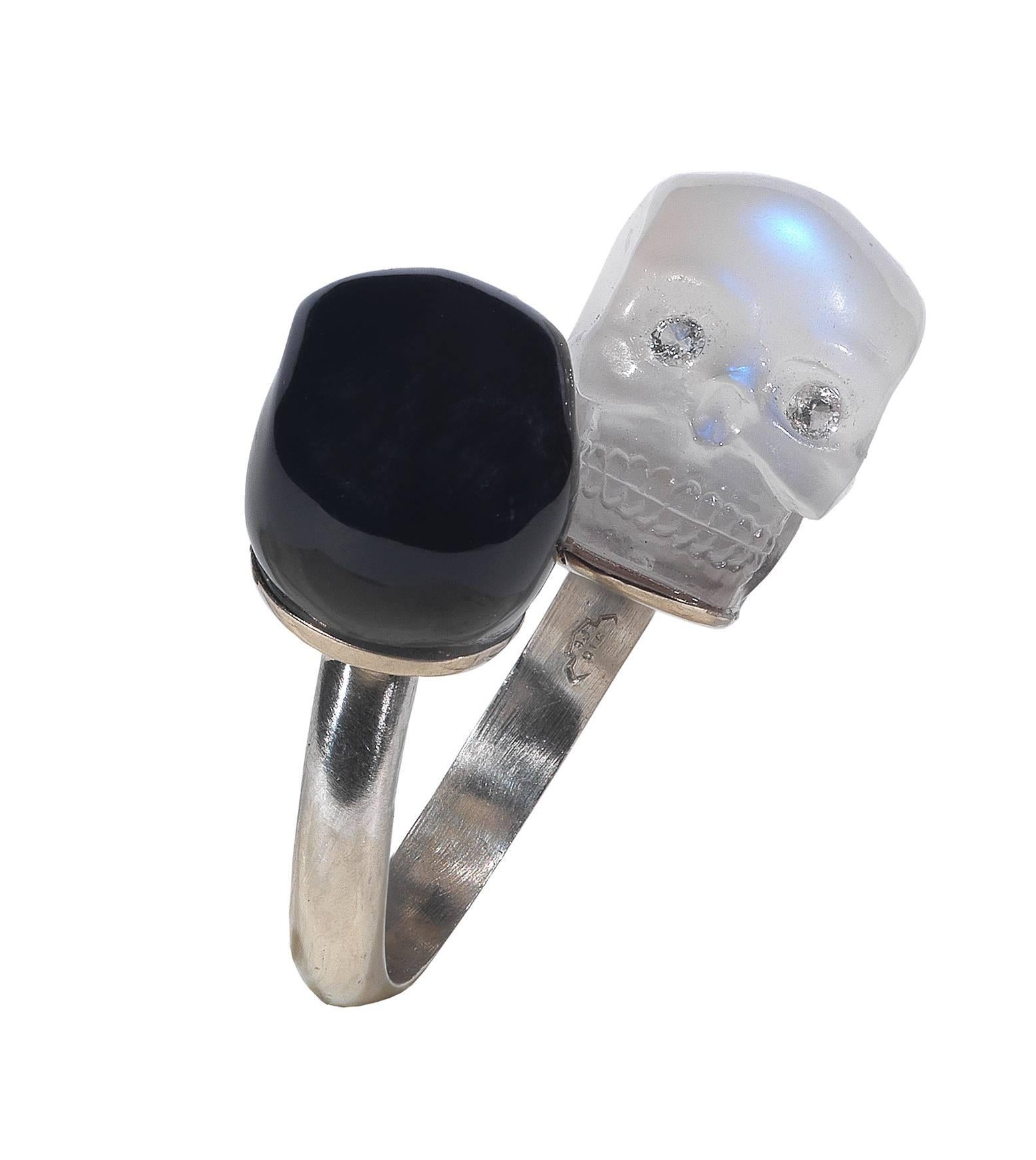 
Designed with two slightly obliquely-set skulls, one moonstone and one onyx both with diamond eyes, each measuring approximately 13 mm. 

Mounted in platinum. 

Finger size: 5 3/4 

Weight: 11.7 gr 