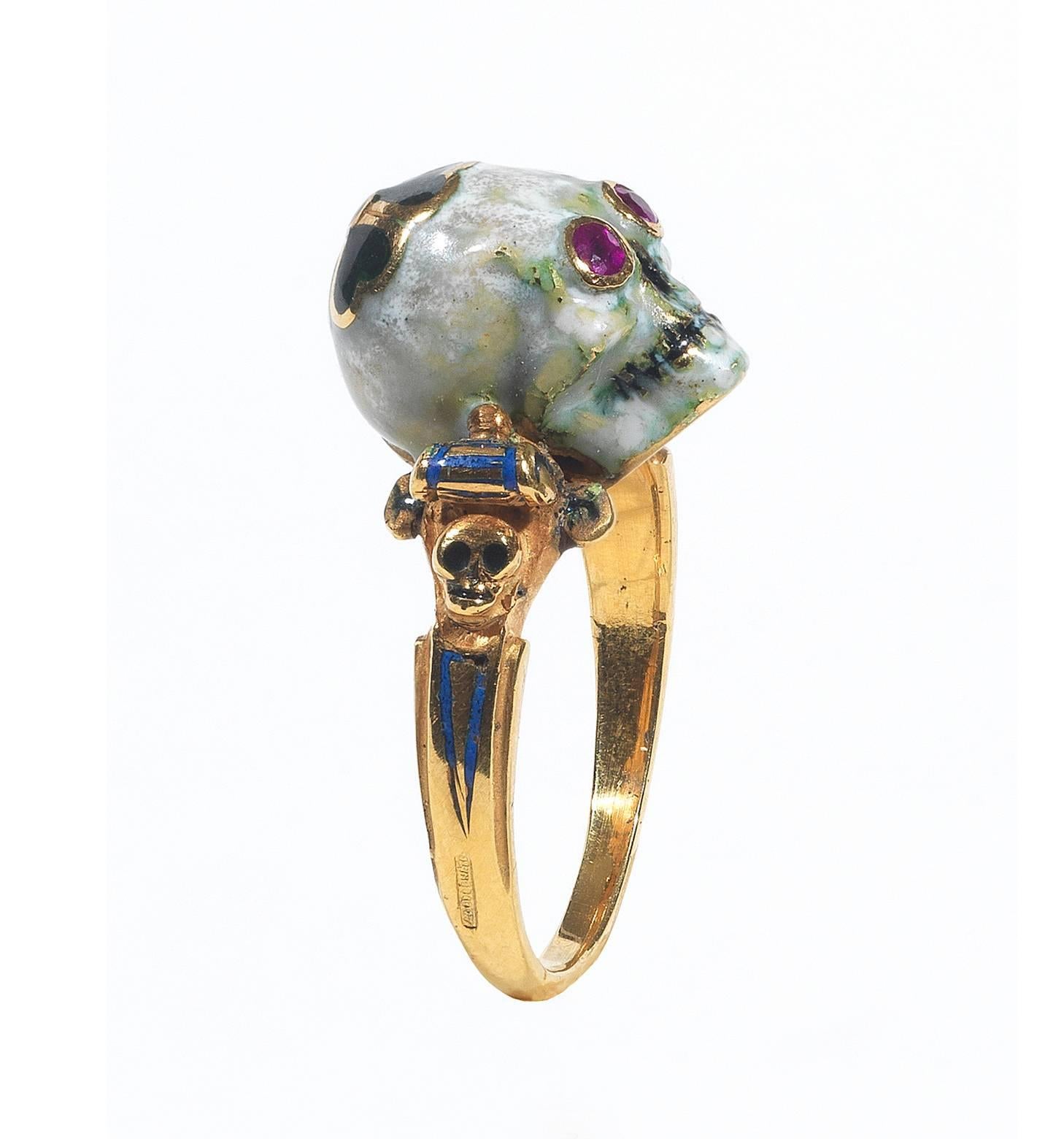 

The ruby eye white enamel Memento Mori skull surmounted by a dark green enamel quatrefoil, the shoulders decorated with small skulls and multi colored enamel scrolls.

Mounted in 18Kt yellow gold 

Signed A. Codognato Venezia

Weight:  7