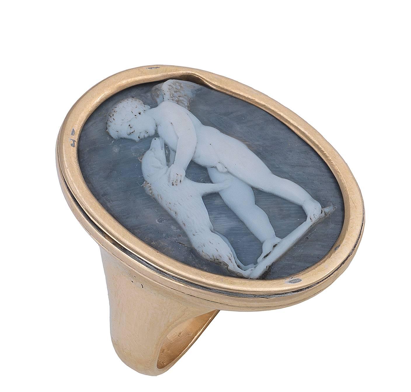 The oval  white on blue grey shell carved to depict the classic scene of a winged Cupid playing with a dog.

Later 18Kt yellow gold mounting

Size of the top: 30.8 mm high

Weight: 19.5 gr

Finger size: 10
