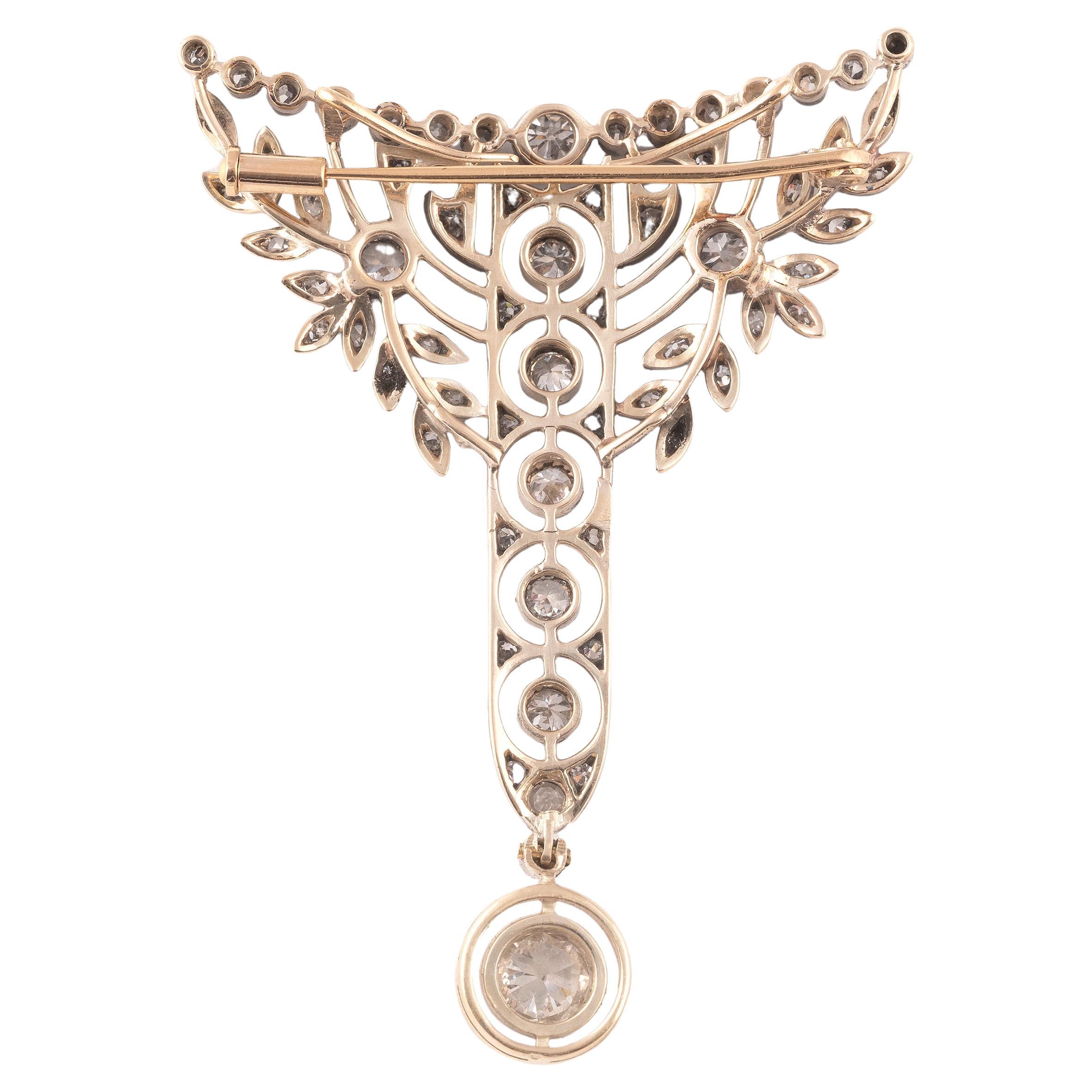 Con diamanti a forma di cuscino, diamanti antichi a brillante e diamanti a taglio singolo, che terminano con una goccia di diamante a forma di cuscino, sospesa a una catena a maglie, tramite un filo a coltello di diamanti antichi a brillante,