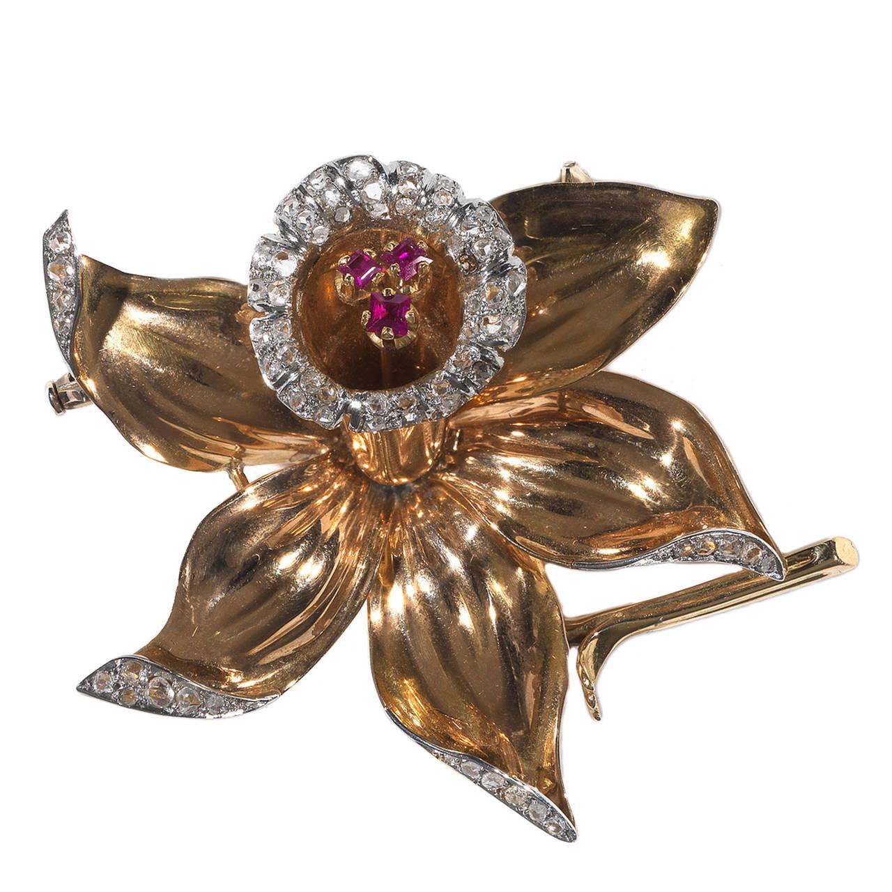 Of flower shape, the borders of the petals and the bud with collet set rose cut diamonds, at the centre of the bud three square cut claw set rubies

Mounted in 18Kt gold and platinum

Weight: 25.3 

56 mm high and wide