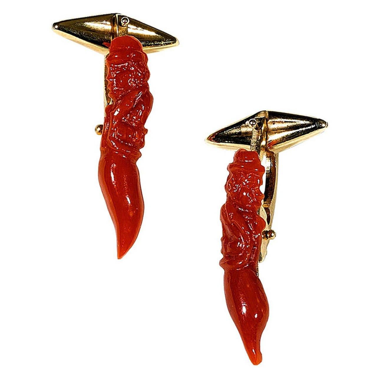 

A pair of cufflinks in coral depicting two gargoyles.