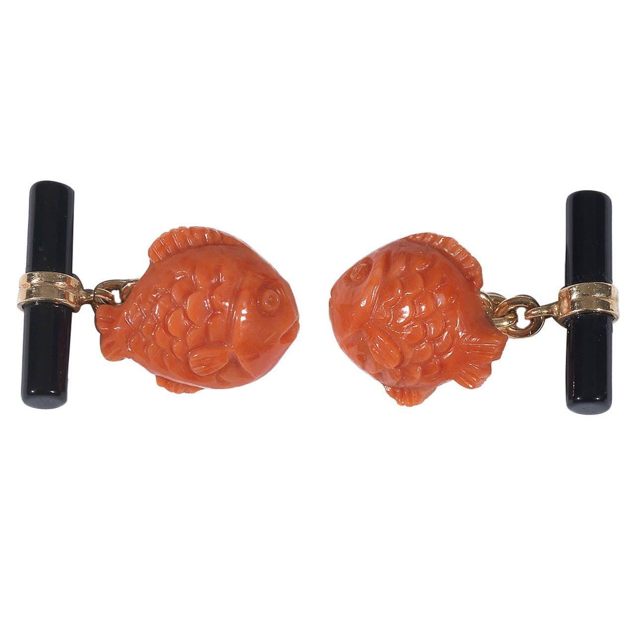
Pair of cufflinks designed as carved coral fish.

Chain link connections with onyx baton.      

Mounted in 18Kt yellow gold