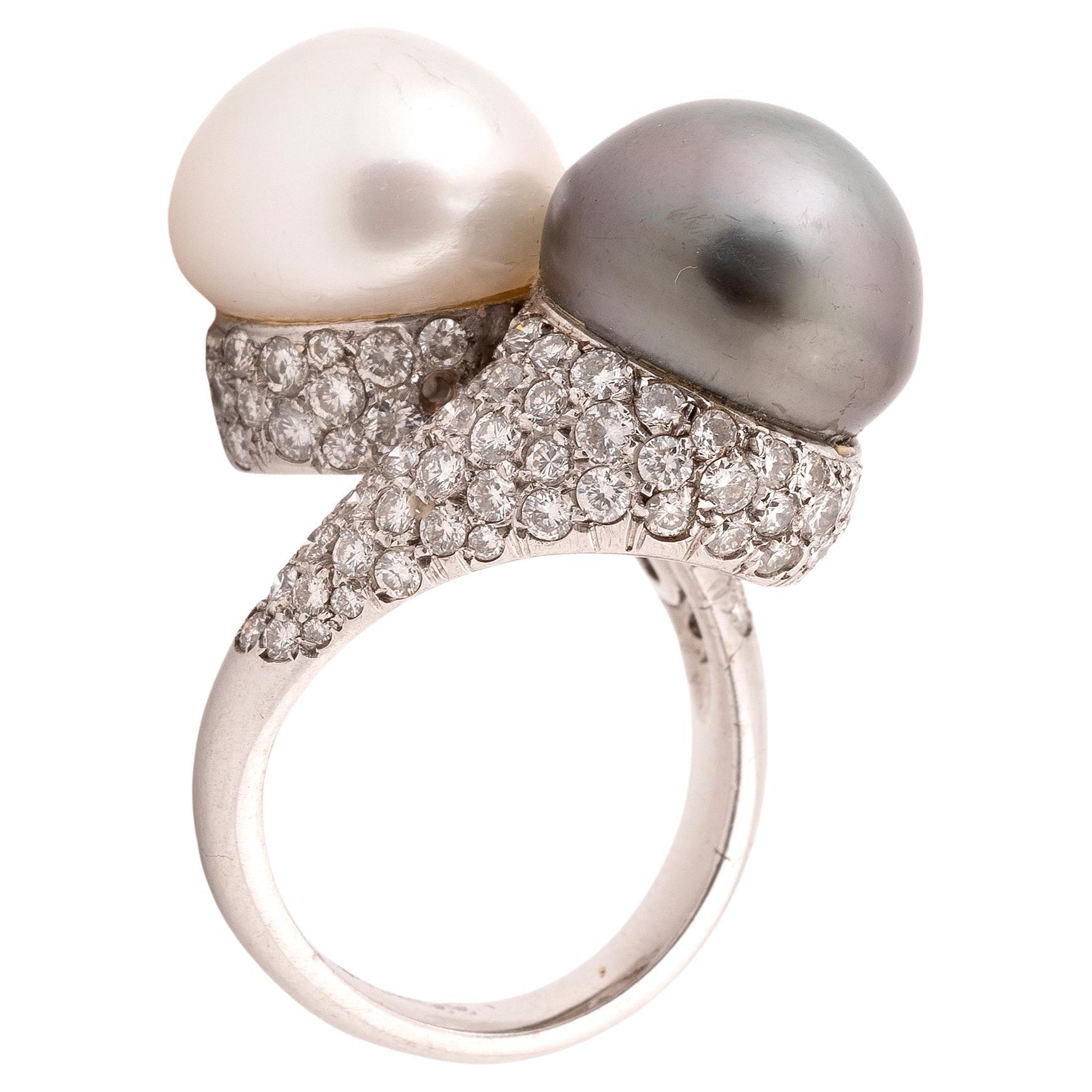
Obliquely-set with two 10.0mm cultured pearls, one of grey tint, between bombé shoulders pavé-set with brilliant-cut diamonds, diamonds approx. 1.50cts total, 
ring size 7
