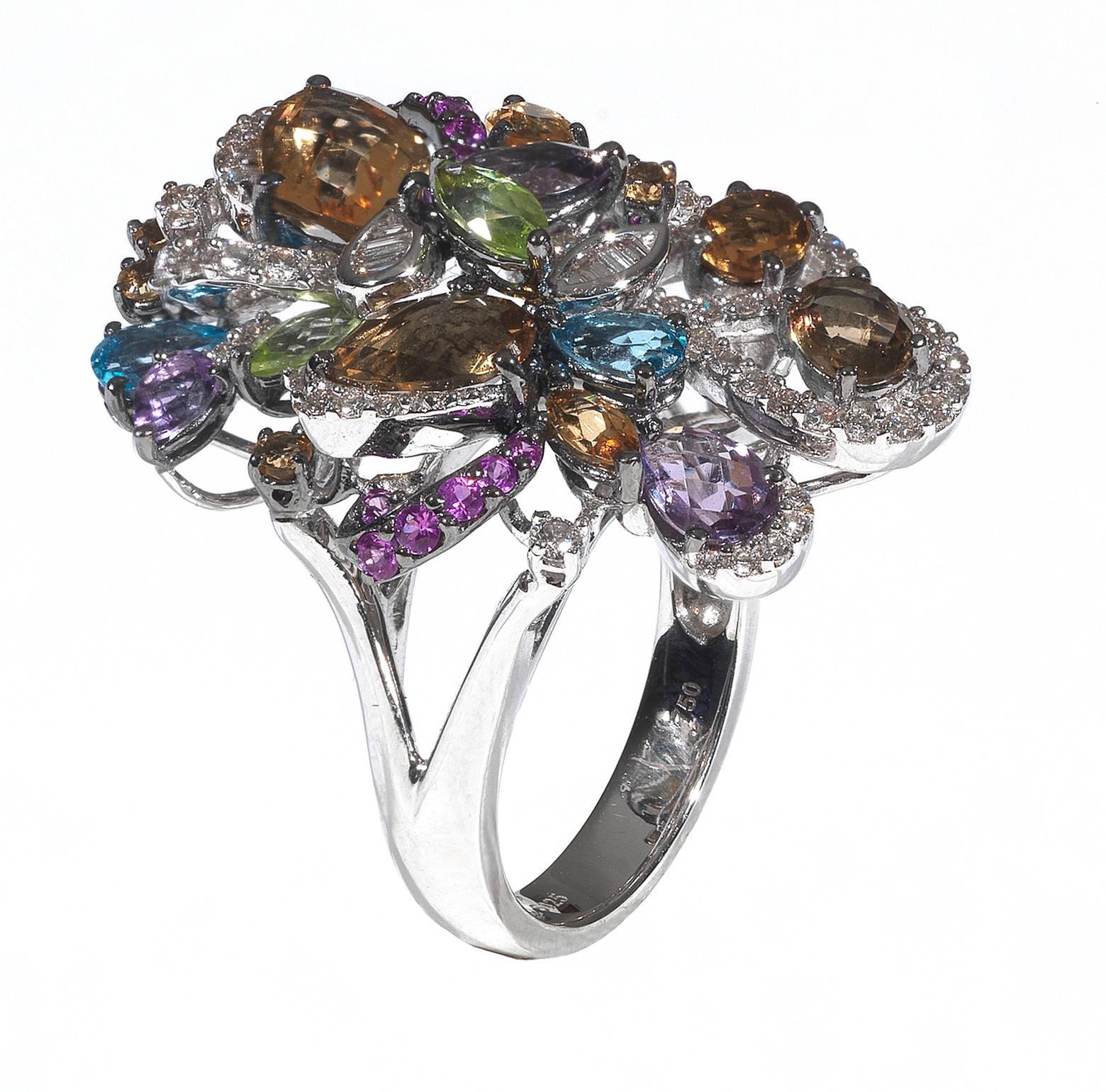 Designed as a floral bouquet with various cuts and colors topazes including oval, drop and round cuts; citrine, green, blu and pink colors; drop and marquise cut amethysts.

Accented by round and baguette cut diamonds

Mounted in 18Kt white