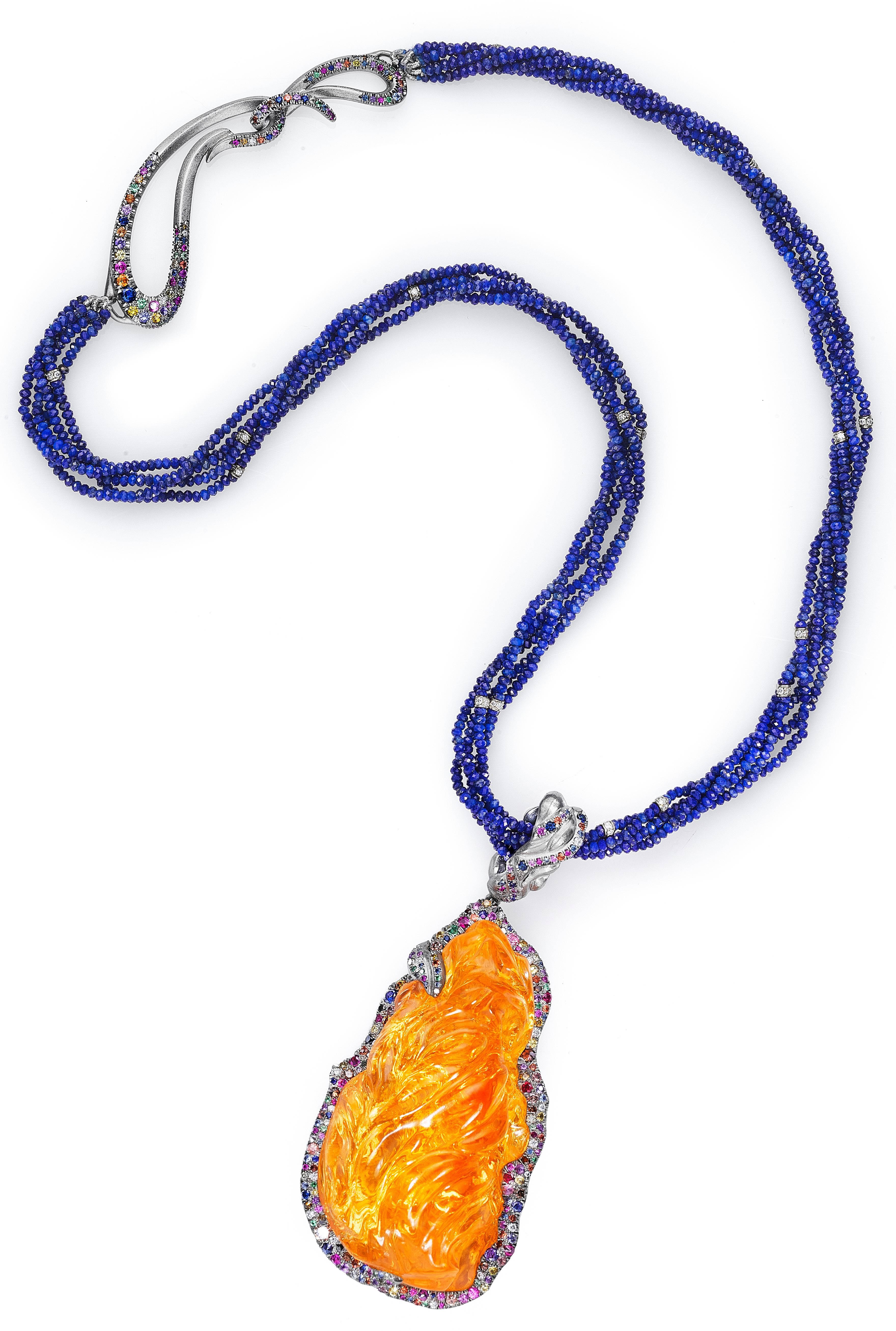 This museum quality pendant is a 108 carat Mexican fire opal hand-carved by Naomi. The opal is of uncommonly large size and good clarity. It is set in hand-crafted 18K natural white gold crusted with bright multicolored diamonds, sapphires, and