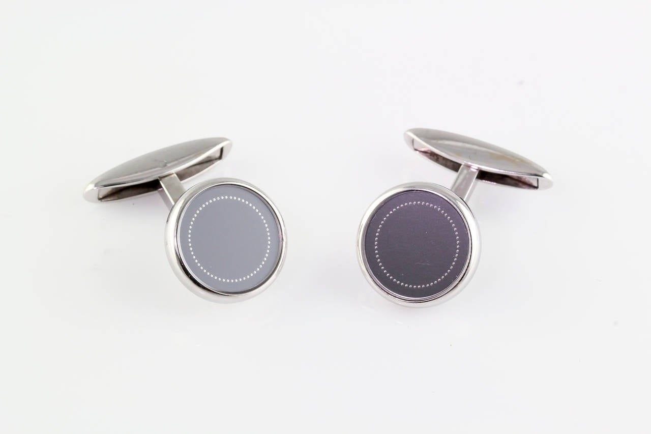 Classic dark gray enamel and 18K white gold round cufflinks by Chopard. The cufflinks feature a finely crafted circular design.
Hallmarks: Chopard, maker's mark, 750.