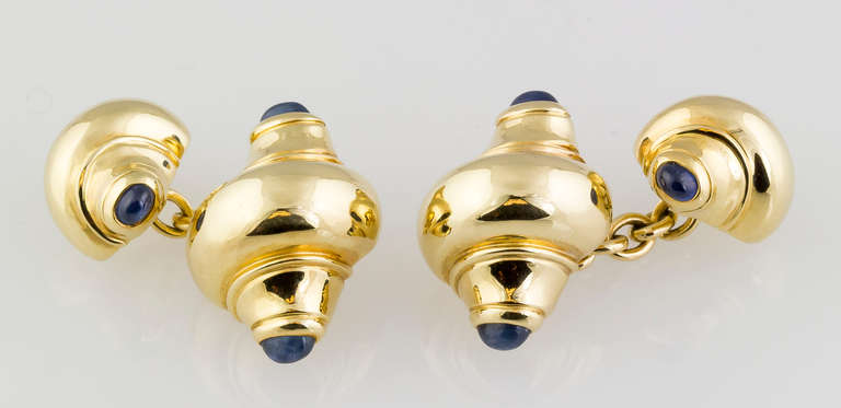 Elegant cabochon sapphire and 18k yellow gold cufflinks by Seaman Schepps. They resemble seashells, with rich blue cabochon sapphires on each end. 
Hallmarks: Seaman Schepps, reference numbers, 750, copyright.