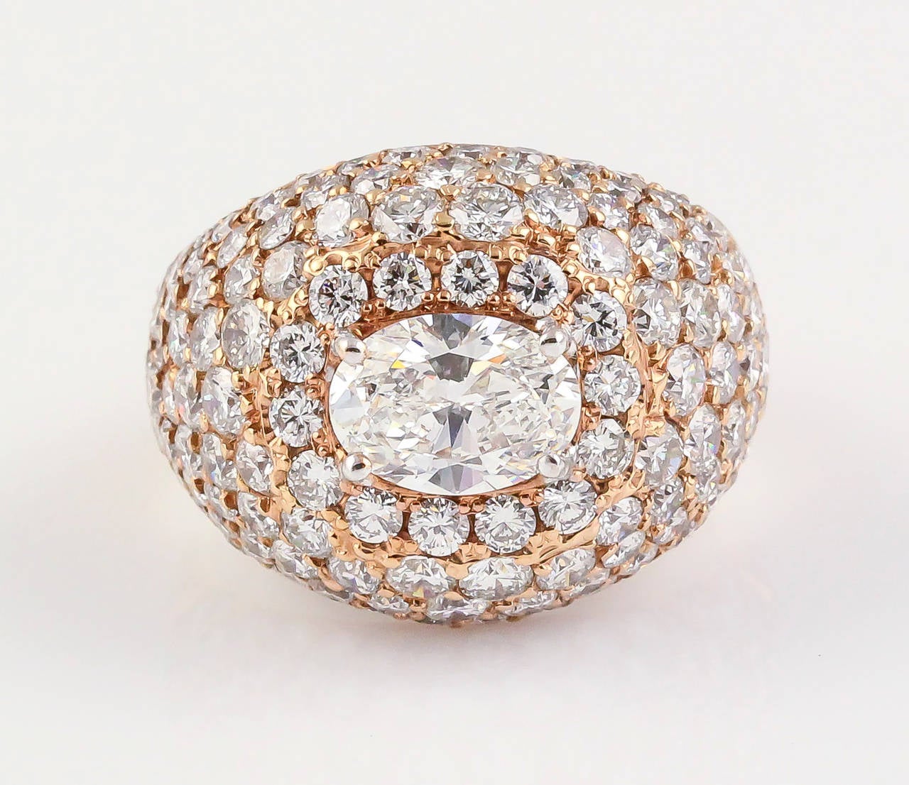 Impressive 18K pink gold and diamond dome ring of French origin. It features very high grade round brilliant cut diamonds, with an oval cut central stone with great clarity and nice color, approx F-G VS1-2 and approx. 1.50cts in weight. The ring is