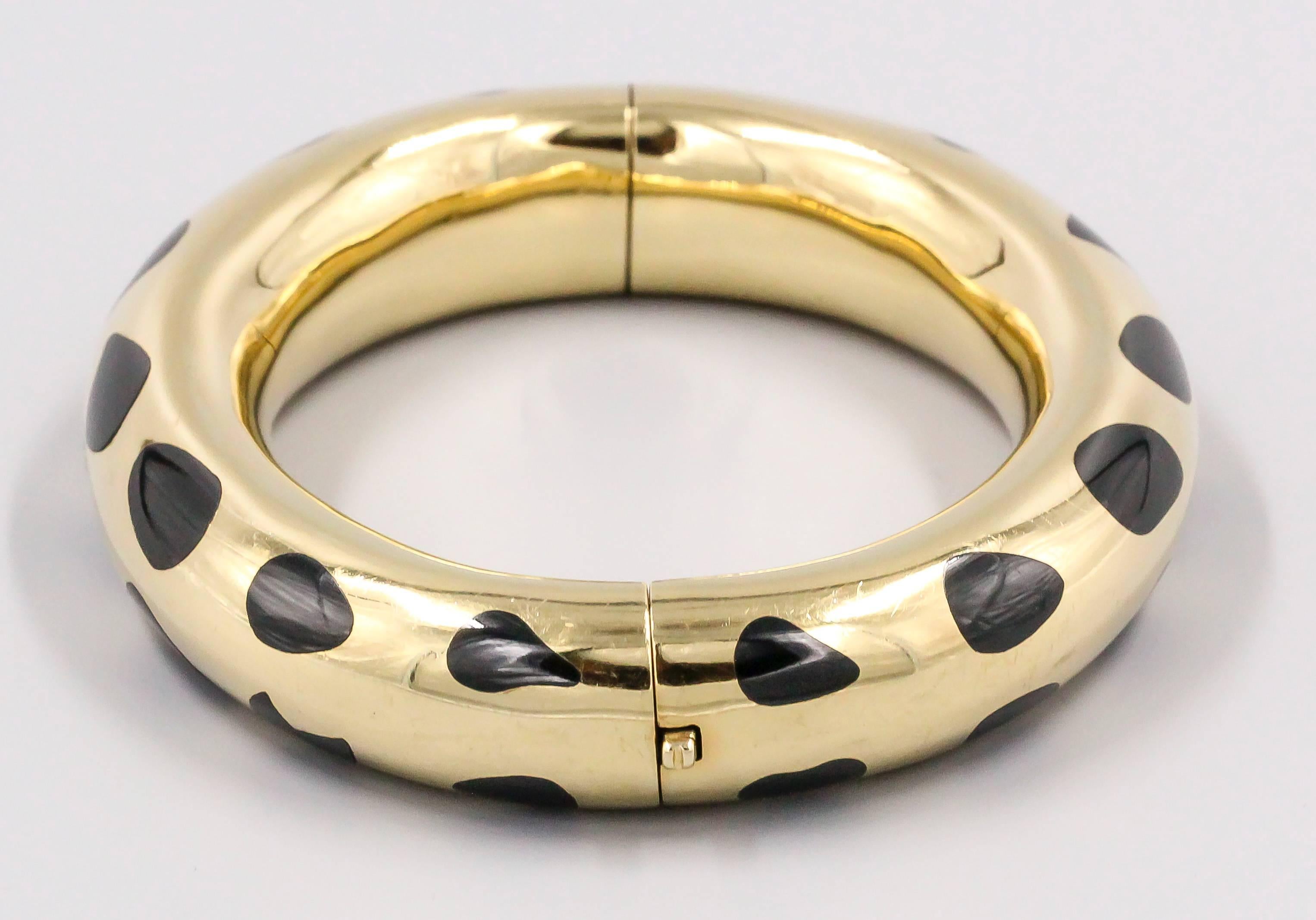 Elegant inlaid black jade and 18K gold bangle bracelet by Tiffany & Co. It features inlaid black jade spots of varying eclecting shapes over a gold base. Beautifully made, with push button opening. Angela Cummings is credited as the designer of this