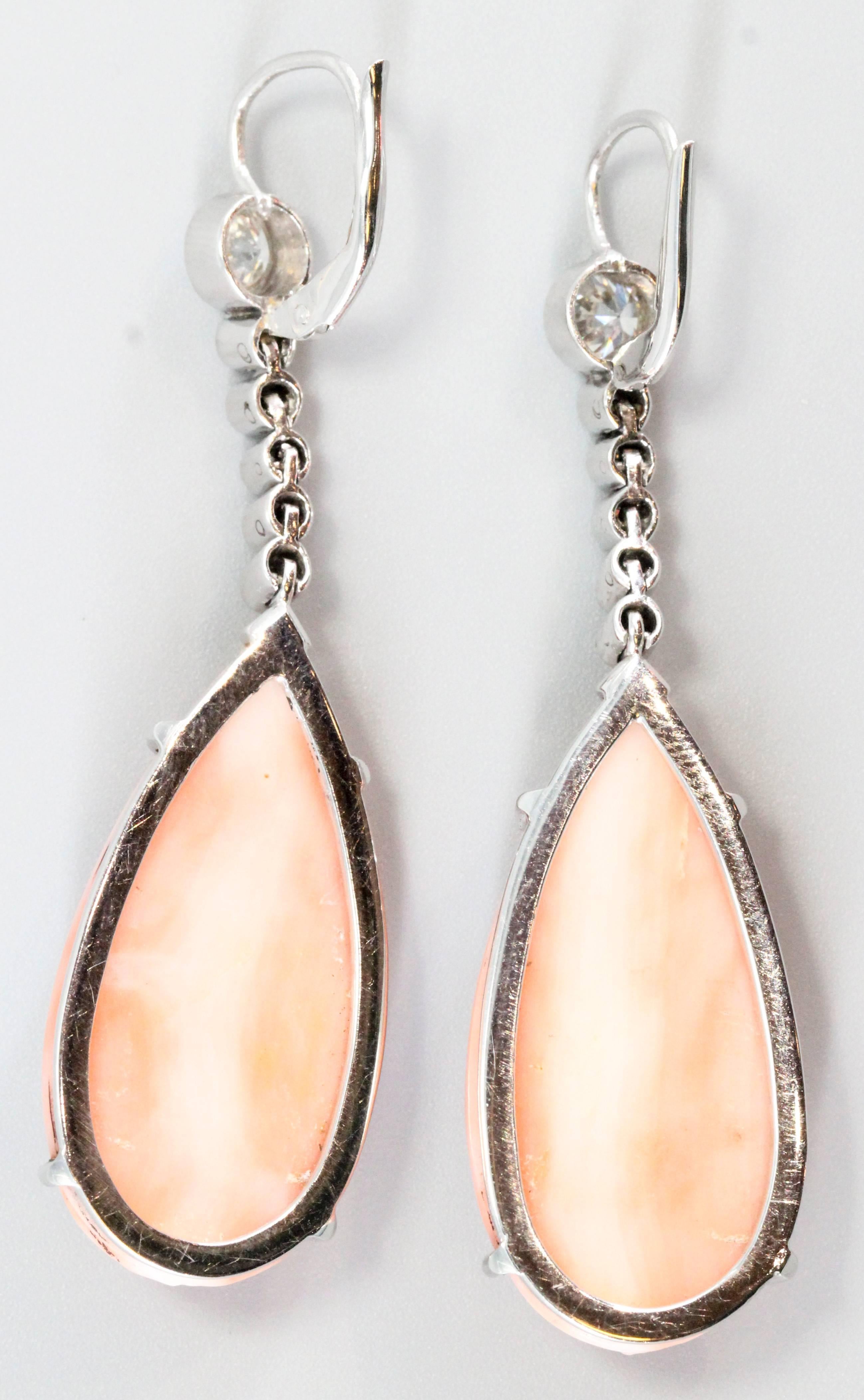 Chic diamond, angel skin coral and platinum ear pendants, circa 1950s. They feature high grade round brilliant cut diamonds, along with a platinum mounting and a beautiful pear shaped, ribbed coral piece at the bottom. Expertly crafted.

