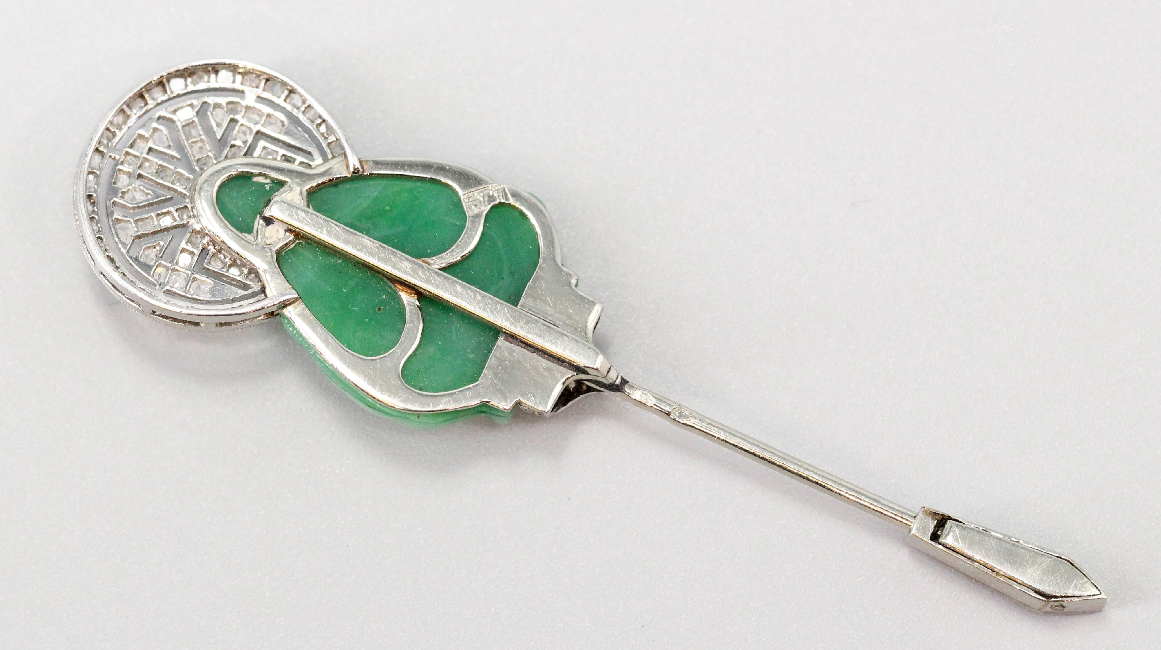 Rare and unusual Art Deco diamond, green stone and platinum jabot pin of French origin, circa 1920s-30s. It features the likeness of a Buddha playing a flute like instrument, made in a carved green stone, with diamonds over a platinum setting.