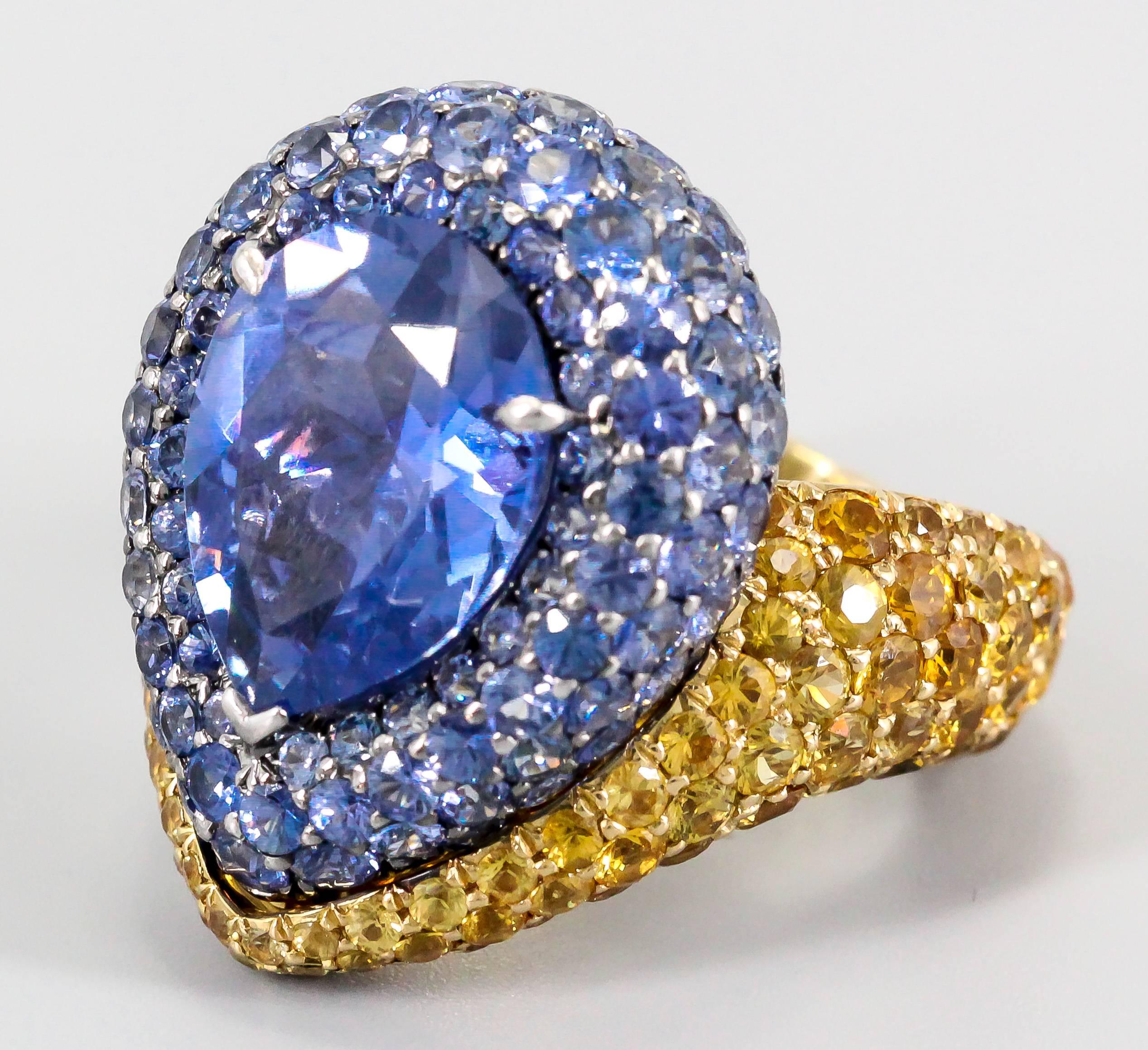 Stylish blue and yellow sapphire and 18K gold ring by De Grisogono. It features a pave of blue sapphires accentuating  a large pear shaped sapphire, with yellow sapphires around the entire outer 18K yellow gold mounting. Very high quality and highly