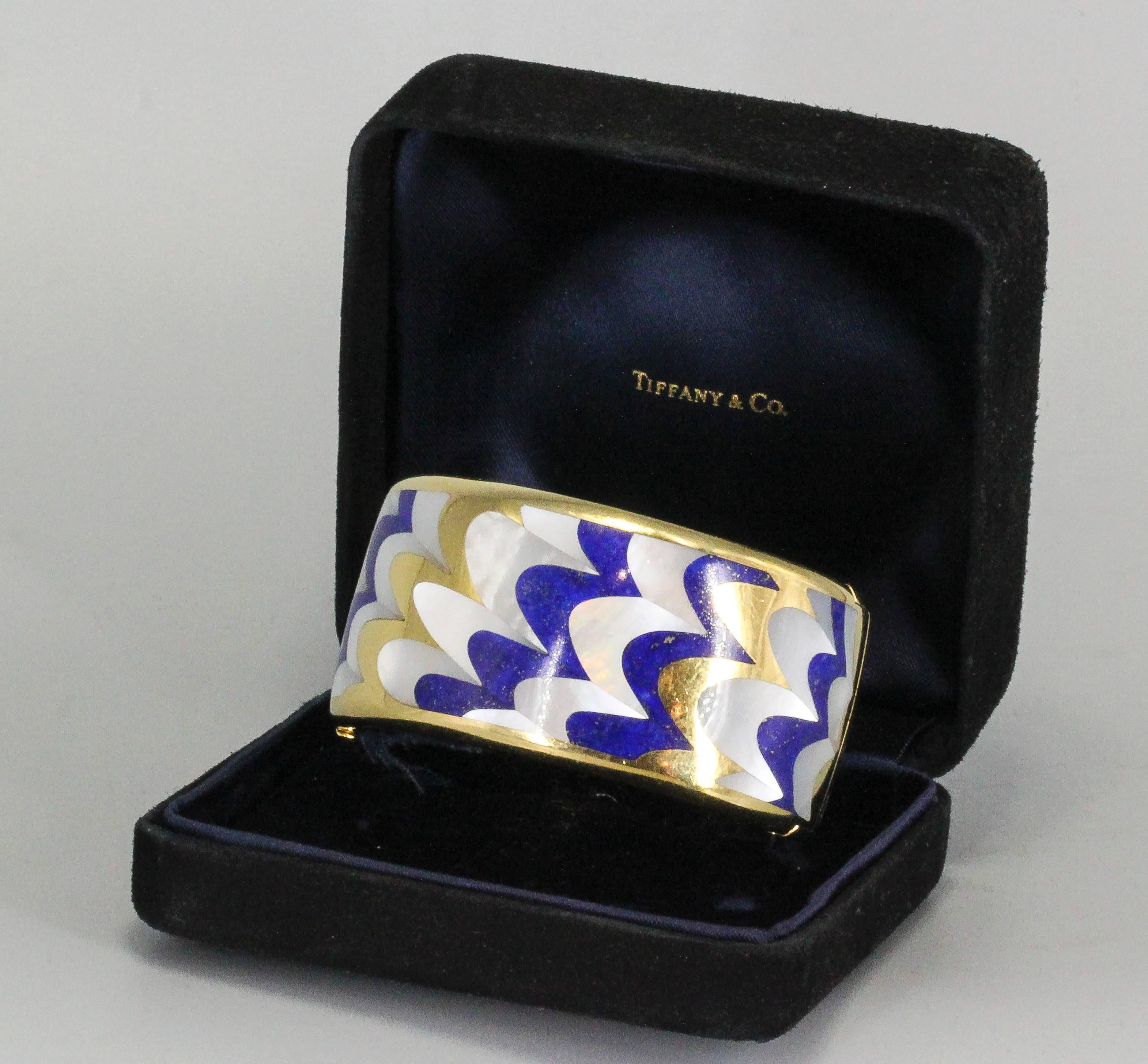 Stylish and highly collectible 18K yellow gold bangle bracelet with inlaid lapis and mother of pearl, by Tiffany & Co. designed by Angela Cummings circa 1970s. It features a highly desirable pattern that is rare and attractive.

Hallmarks: T &