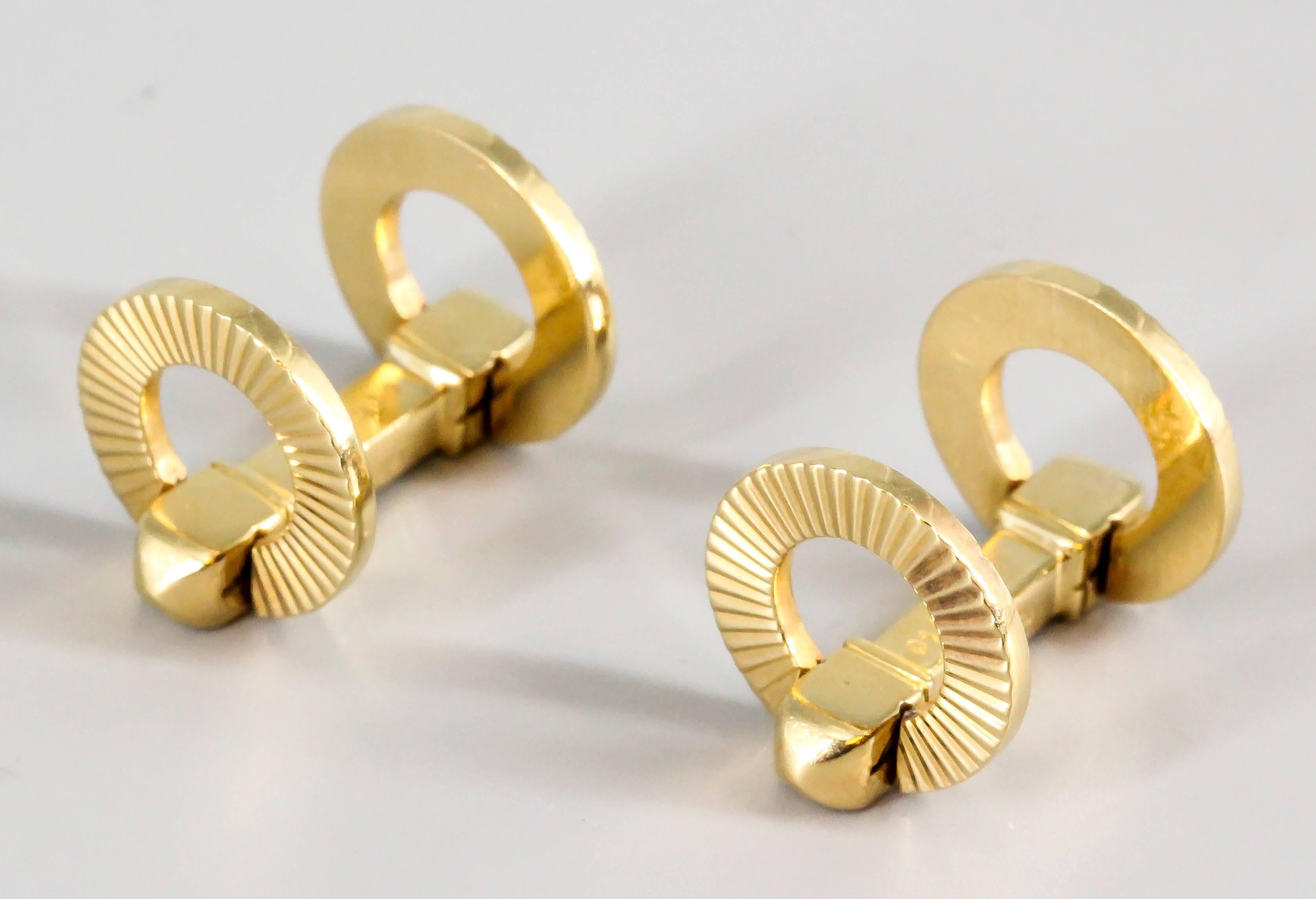 Handsome 18K yellow gold folding cufflinks by Cartier, circa 1950s. They feature a folding mechanism and have a circular coin-edged ribbed design, the opposite side has a polish gold design, either can be used can alternatively. 
Excellent make and