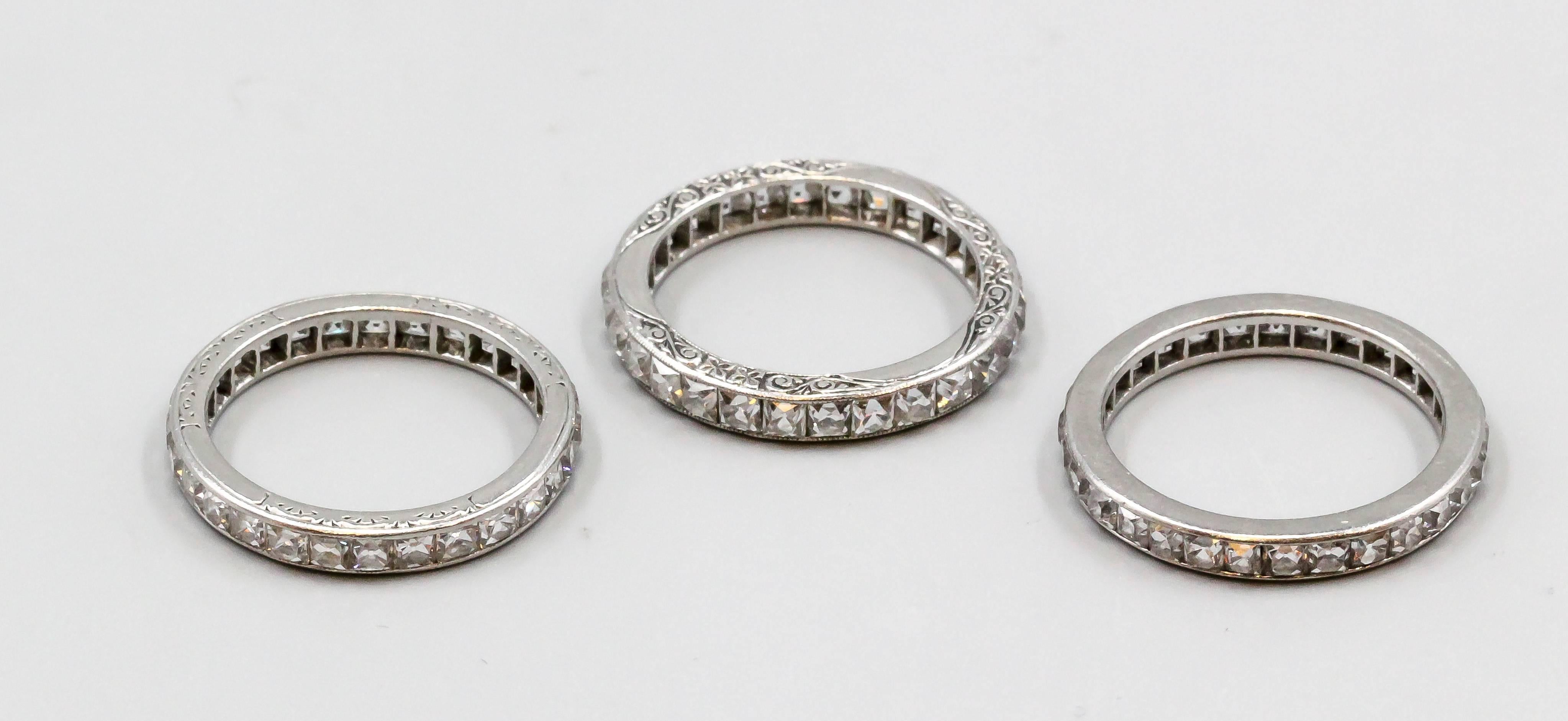 Rare set of three Art Deco era diamond and platinum band set. They feature good quality French cut diamonds within each band, with platinum setting. The two "outer" bands have period carvings in the platinum. Beautiful matching set with