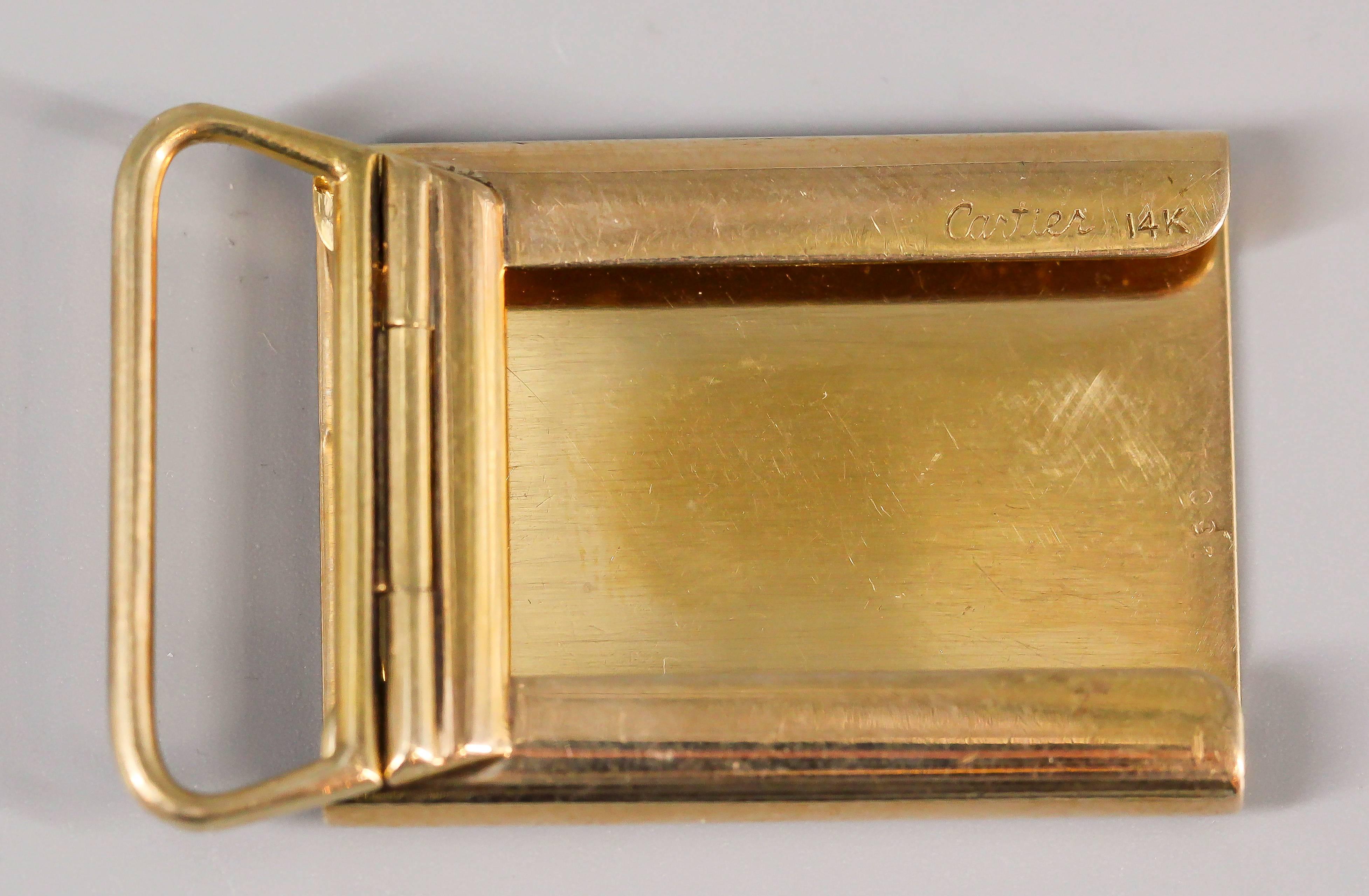 Whimsical 14K yellow gold belt buckle by Cartier, circa 1950s. It features an engine turned pattern front.  Handsomely made and highly usable. 

Hallmarks: Cartier, 14k, reference numbers.