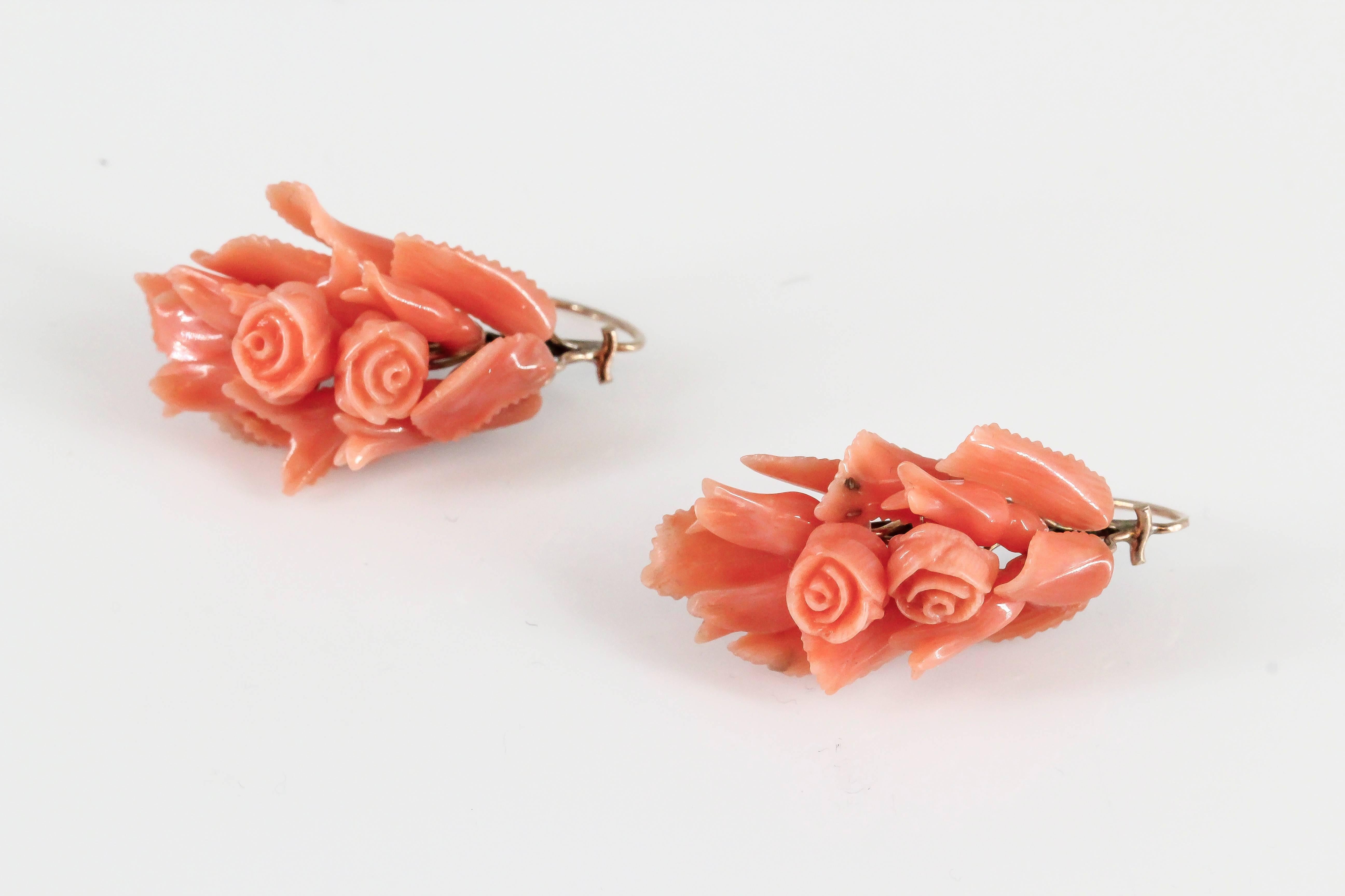 Elegant coral and yellow gold brooch and earrings set, circa 1850s. They feature beautiful workmanship in the coral, which resembles a bouquet of roses with gold setting, with the brooch centering on a cherub. 

