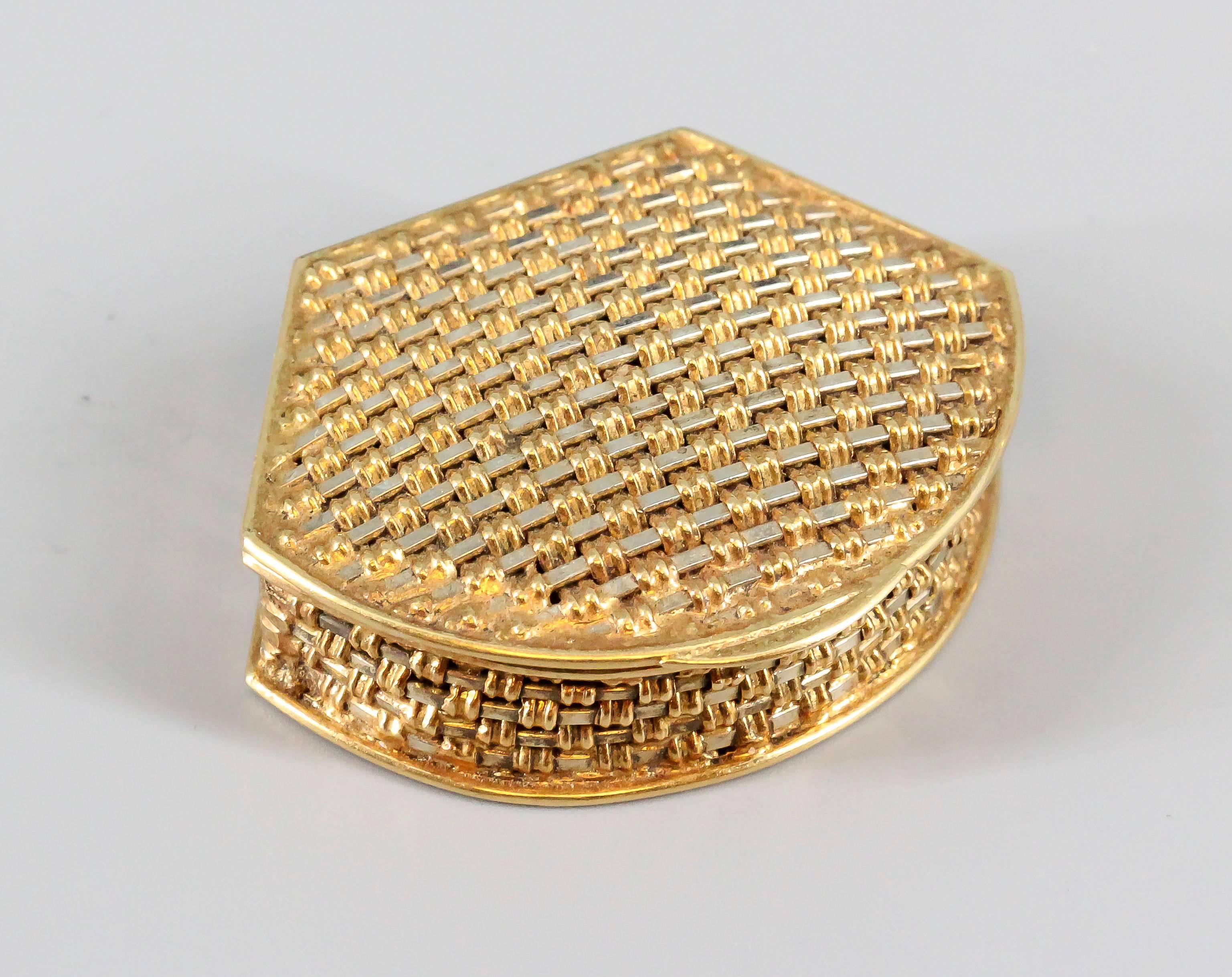 Elegant 18K white and yellow gold basket weave design pill box of Italian origin.
It features a clamshell like shape, with intricately weaved gold strands of white and yellow. 
