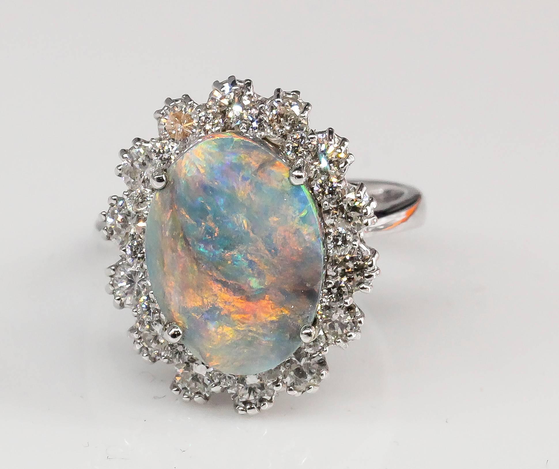 Chic black opal, diamond and 18K white gold dome ring. It features a large oval shaped approx. 4.50 carat black opal as the focal point and flanked by approx. 1.00 carats of high grade round brilliant cut diamonds,  all set in 18K white gold.
