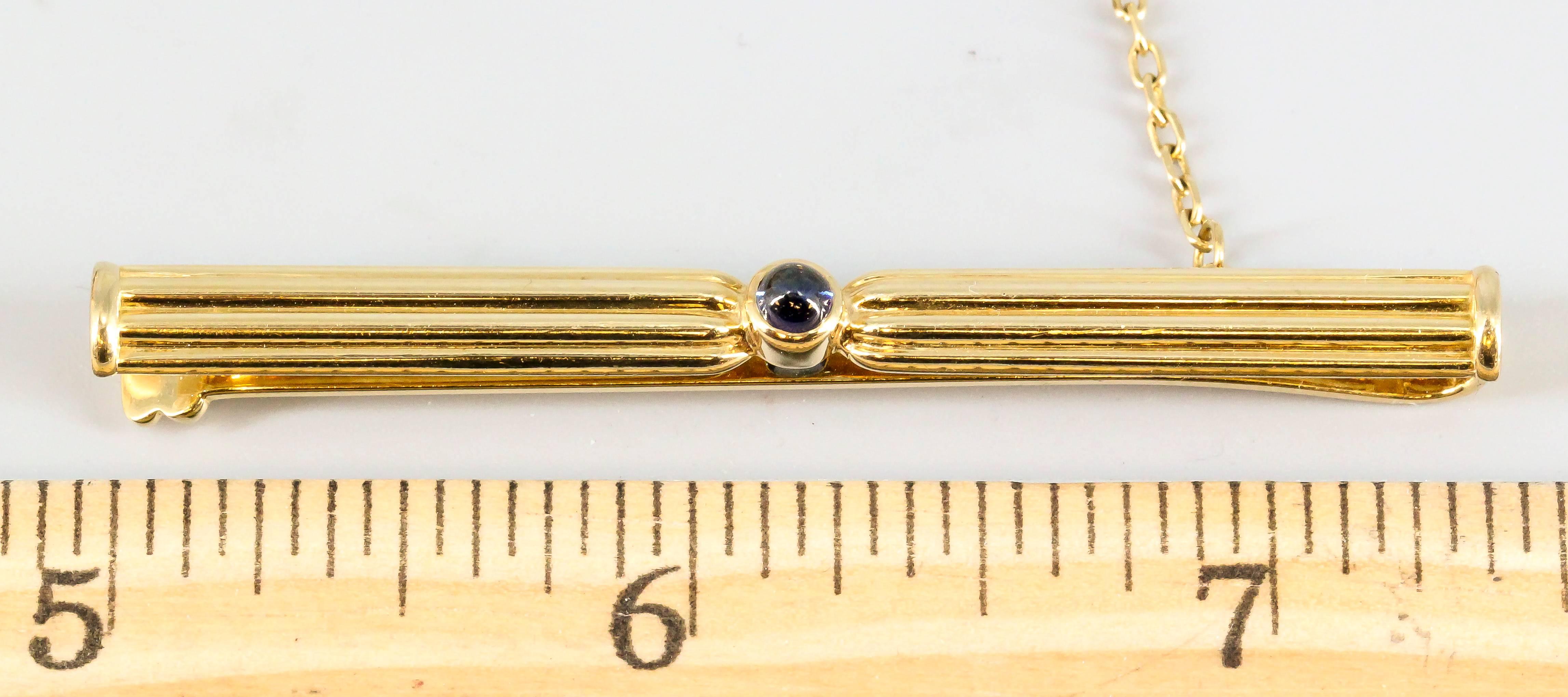 Distinctive cabochon sapphire and gold tie clip from the "Pasha" collection by Cartier circa 1991. It features a single rich blue cabochon sapphire in the middle, with a ribbed 18K yellow gold design. Handsome and craftily made.  Comes