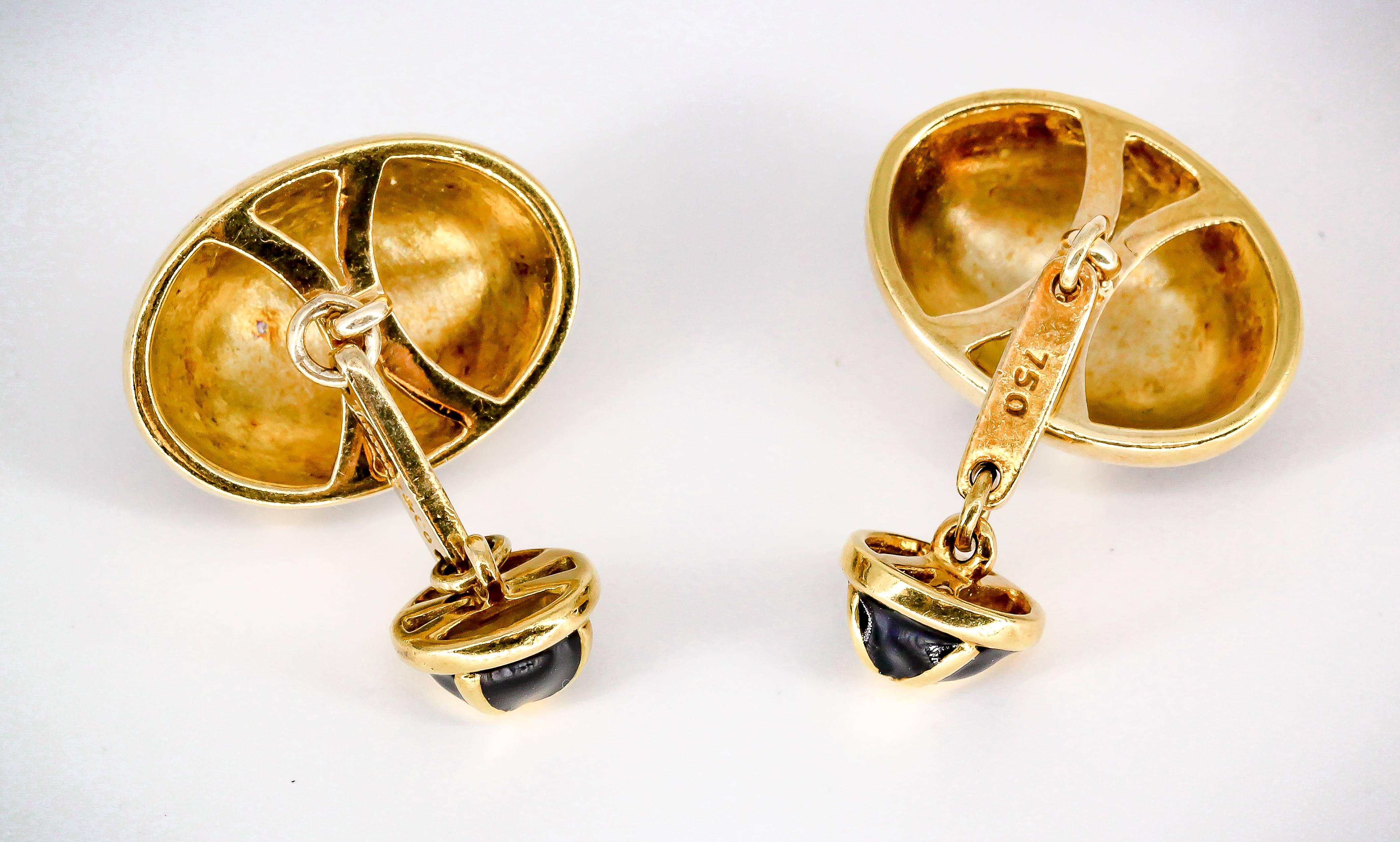 Handsome black enamel and 18K yellow gold cufflinks by Tiffany & Co. Shaped like ovals on one end and rounds on the other, with black enamel over an 18K yellow gold 