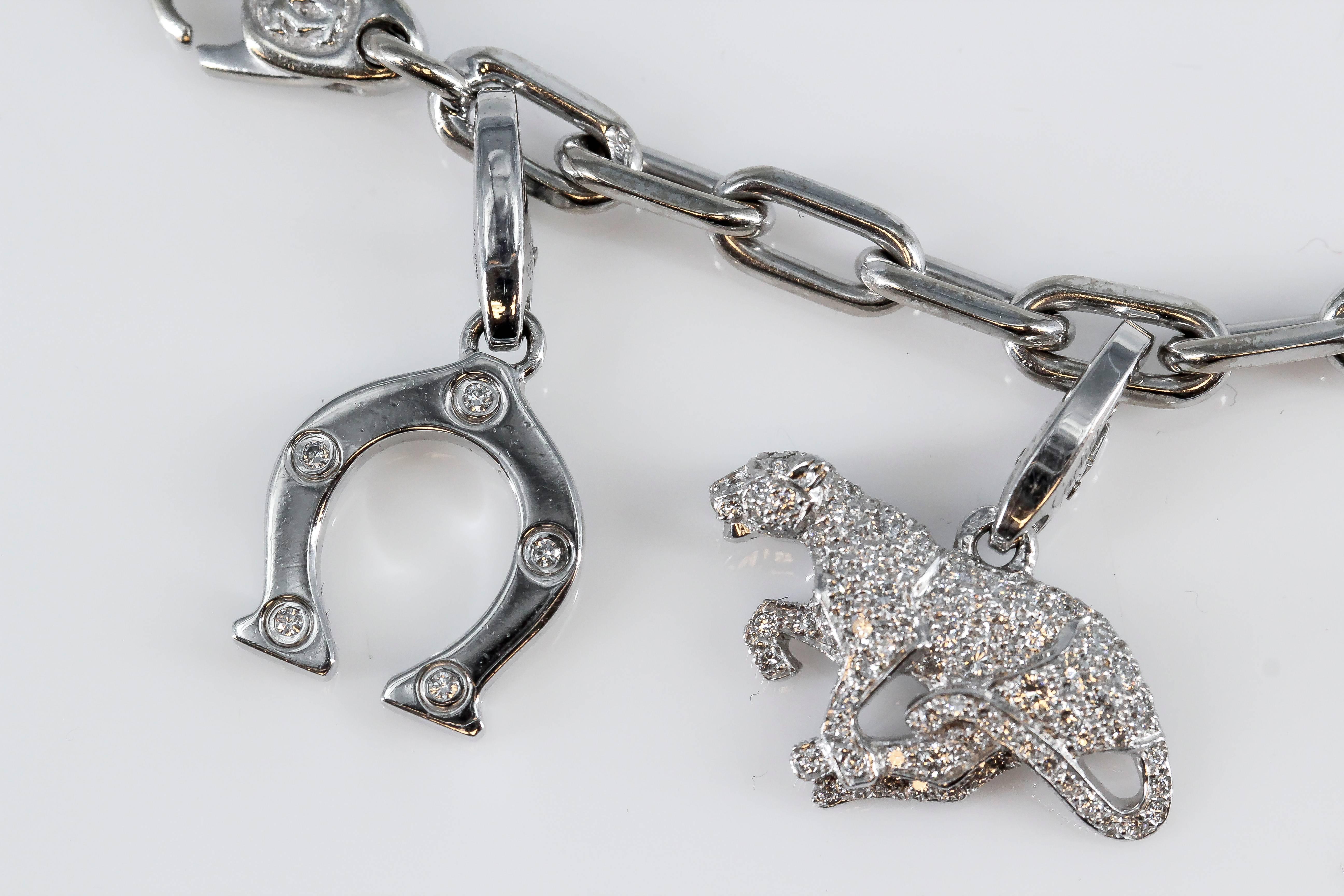 Beautiful diamond and 18K white gold charm bracelet by Cartier. It features 9 charms in total, all diamond set, including: Cartier logo, elephant, love bracelet, revolving "I love you" charm, shamrock, panther, cross, two-tone collapsing