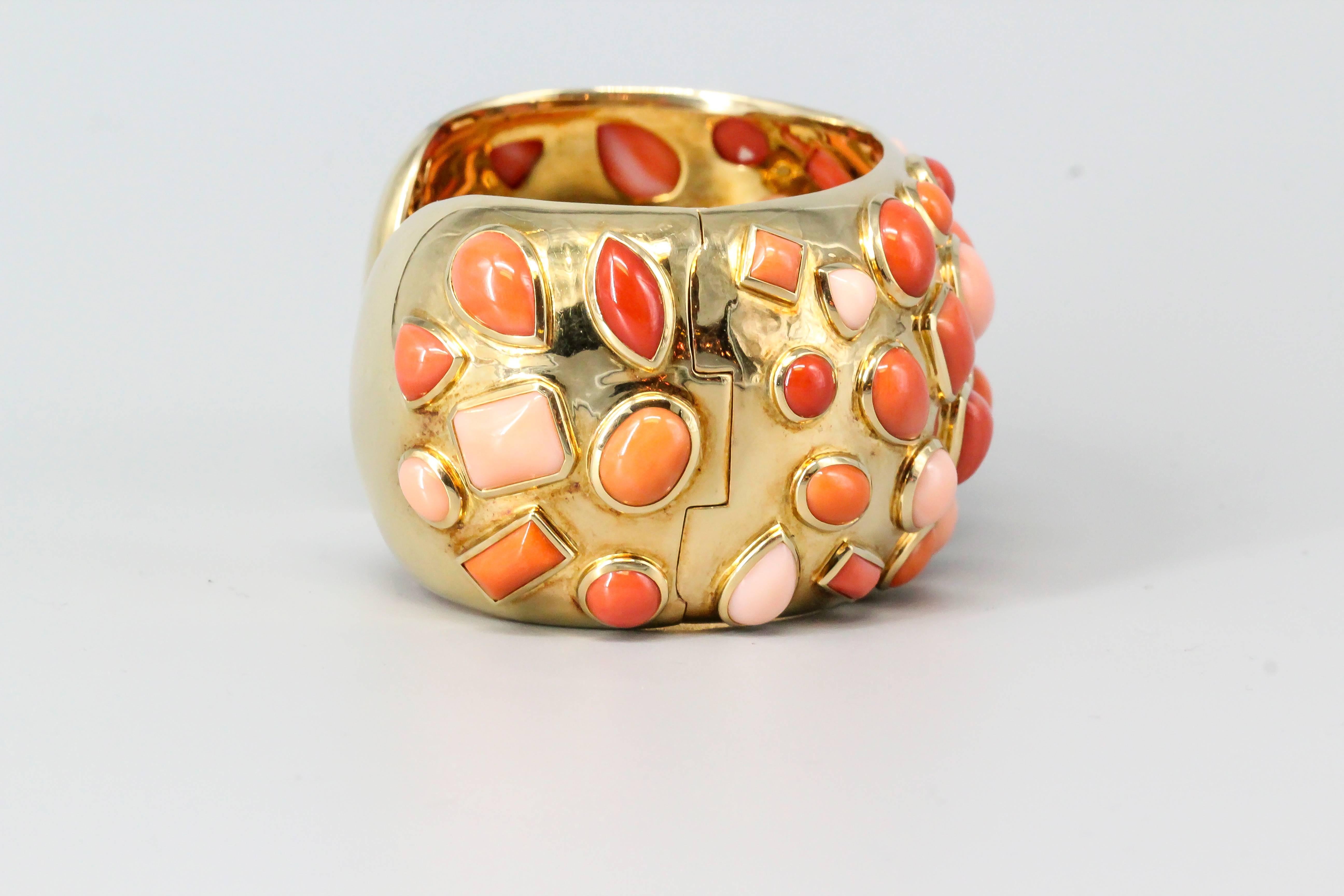Vibrant coral and 18K yellow gold cuff bracelet from the "Fifties" collection, by Seaman Schepps. It features various geometric shaped inserts with different shades of coral pieces, from lighter to darker. Highly ornate and intricate with