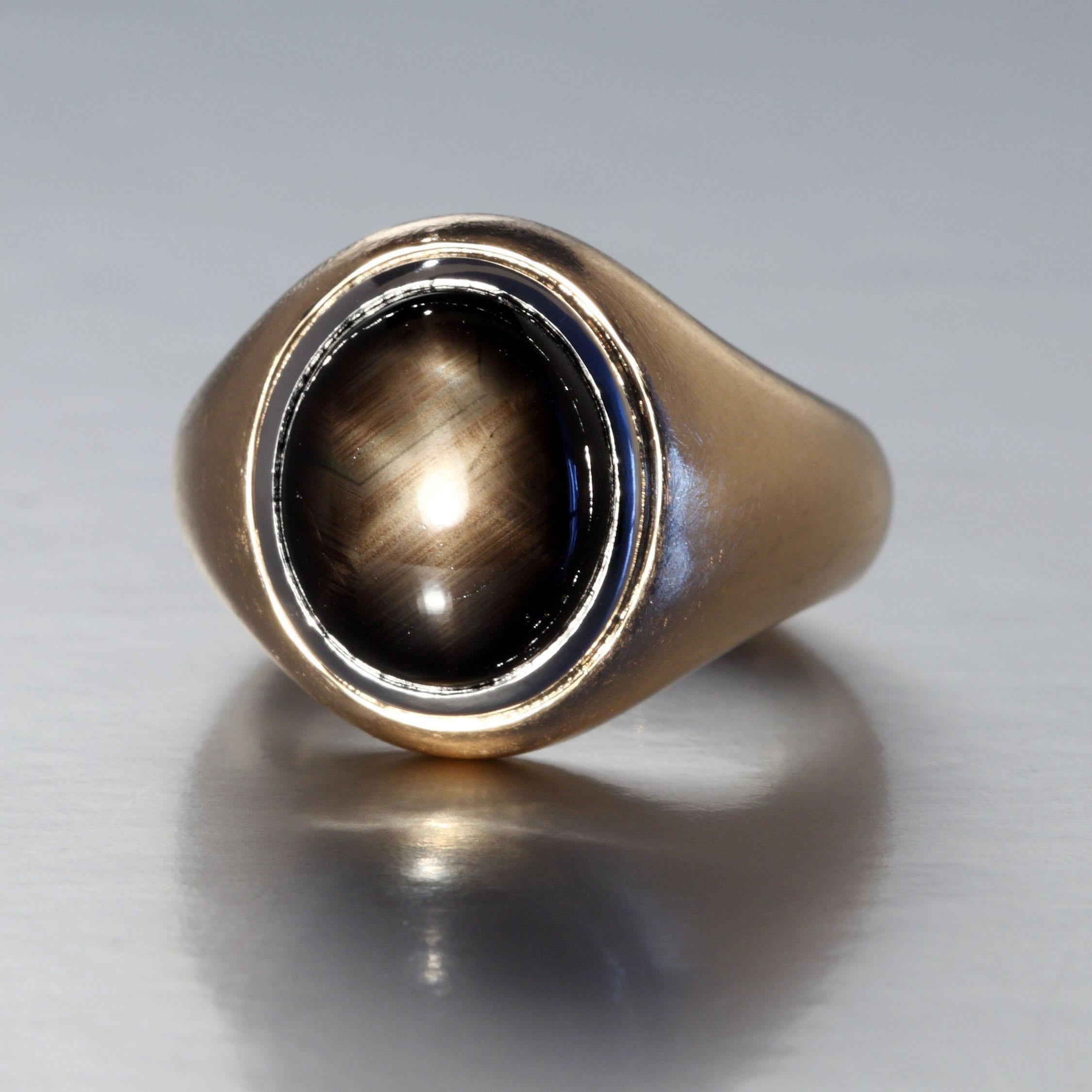 The 11.66 carat oval cabochon cut black star sapphire is set in a platinum rim and mounted in a rose gold ring with a matt finish. An inner spring moves easily over the knuckle and holds the ring in place. This one of a kind piece is designed and