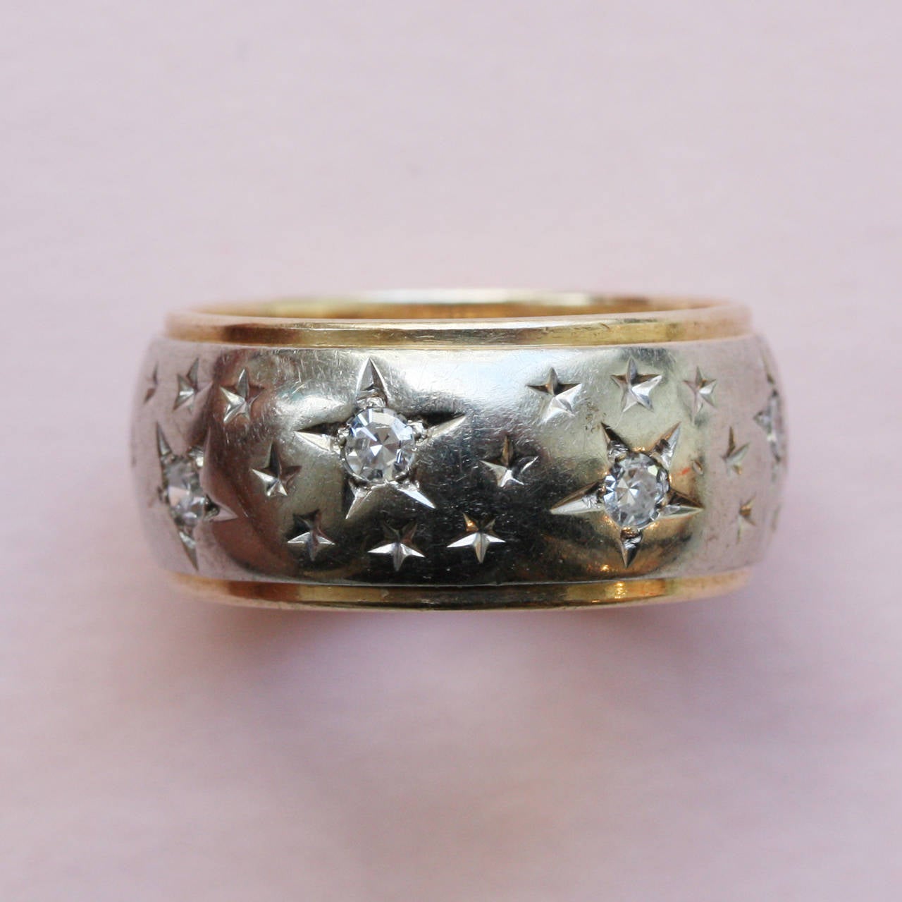 A 14 carat white and yellow gold band ring set with 8 single cut diamonds (total circa 0.5 carats) with engravings that make them stars, USA, 1959.

weight: 8.2 grams
ring size: 16.25 mm. 5 3/4 US.