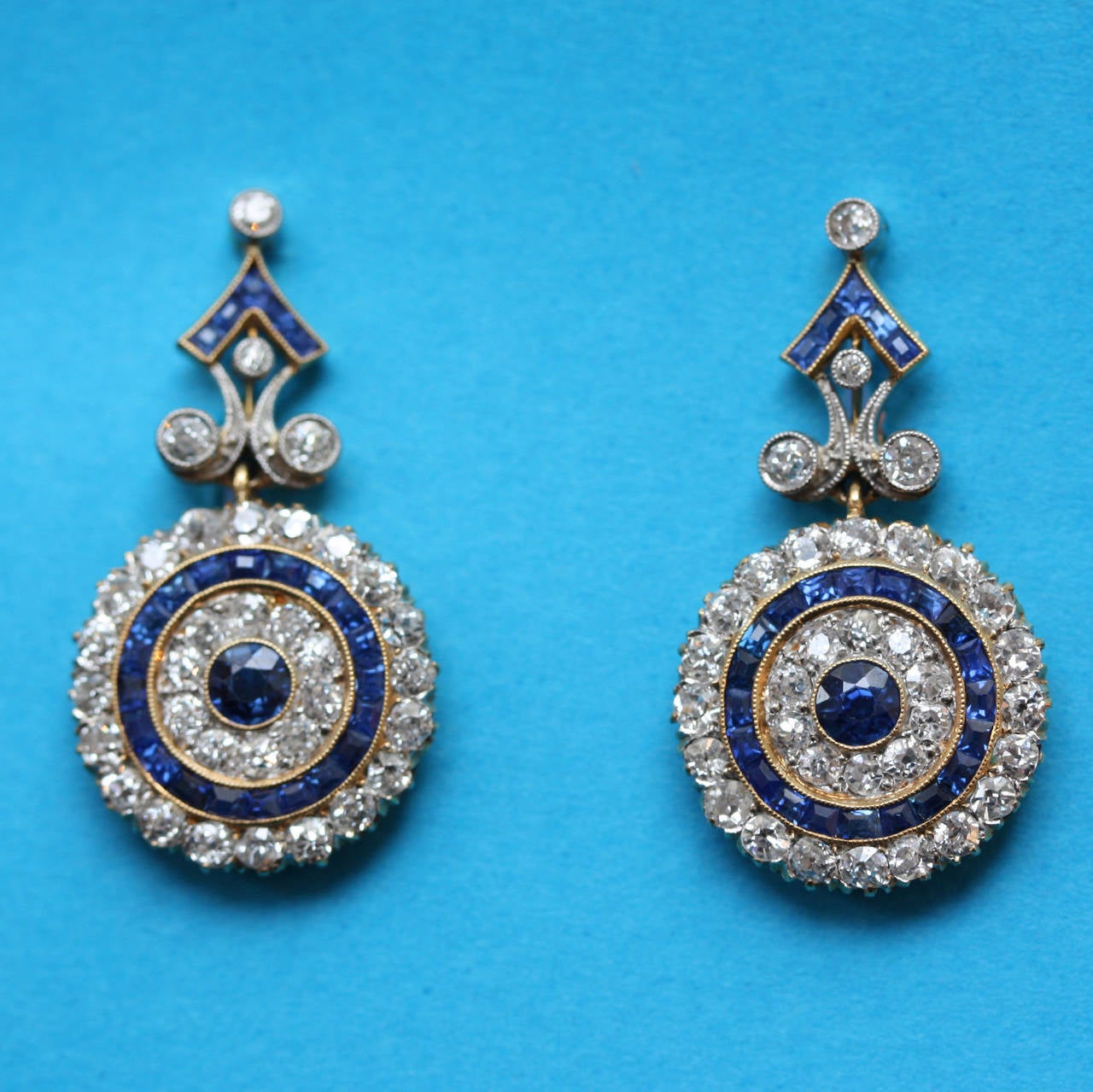 A pair of Edwardian target earrings in 18 carat yellow gold and platinum set with brilliant cut diamonds (circa 2.7 carats) and carré cut and pave set sapphire, numbered, circa 1910, England.

weight: 7.8 grams
dimensions: 3 x 1.7 cm.