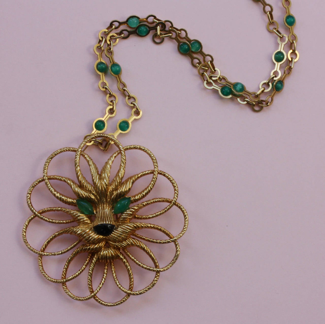 A marvelous 18 carat gold lion pendant (and brooch). Its whiskers and manes are designed in circles of textured gold that go around his face, with an onyx nose and chrysoprase eyes, on a 18 carat gold and chrysoprase bead long chain, both signed and