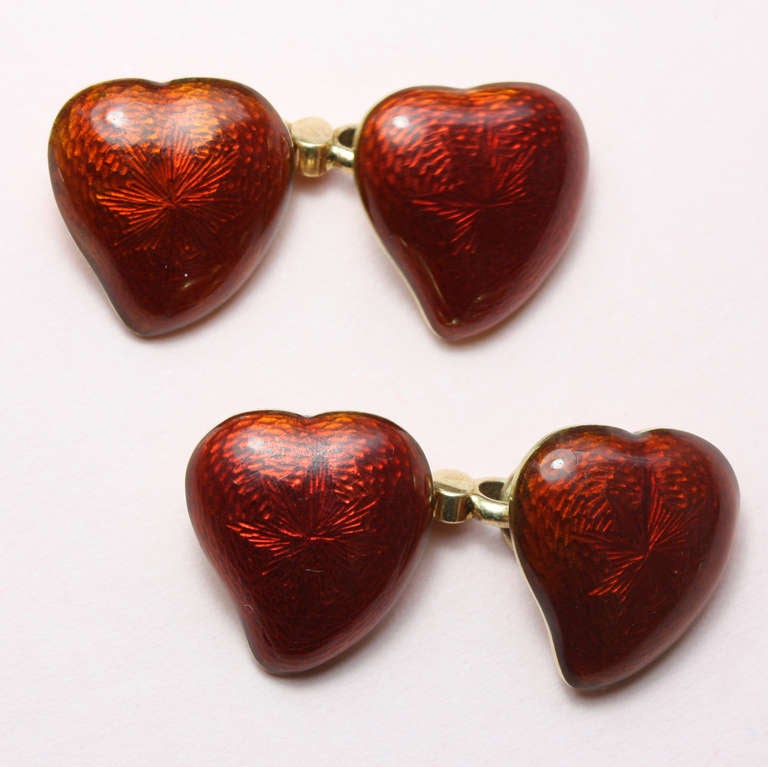 A pair of yellow gold cufflinks in the shape of hearts with red translucent enamel over a guilloche, joined by Giuliano's typical figure of eight links, signed 'C.G' to the links, London, circa 1890.

Literature: 'The Triumph of Love, jewellery