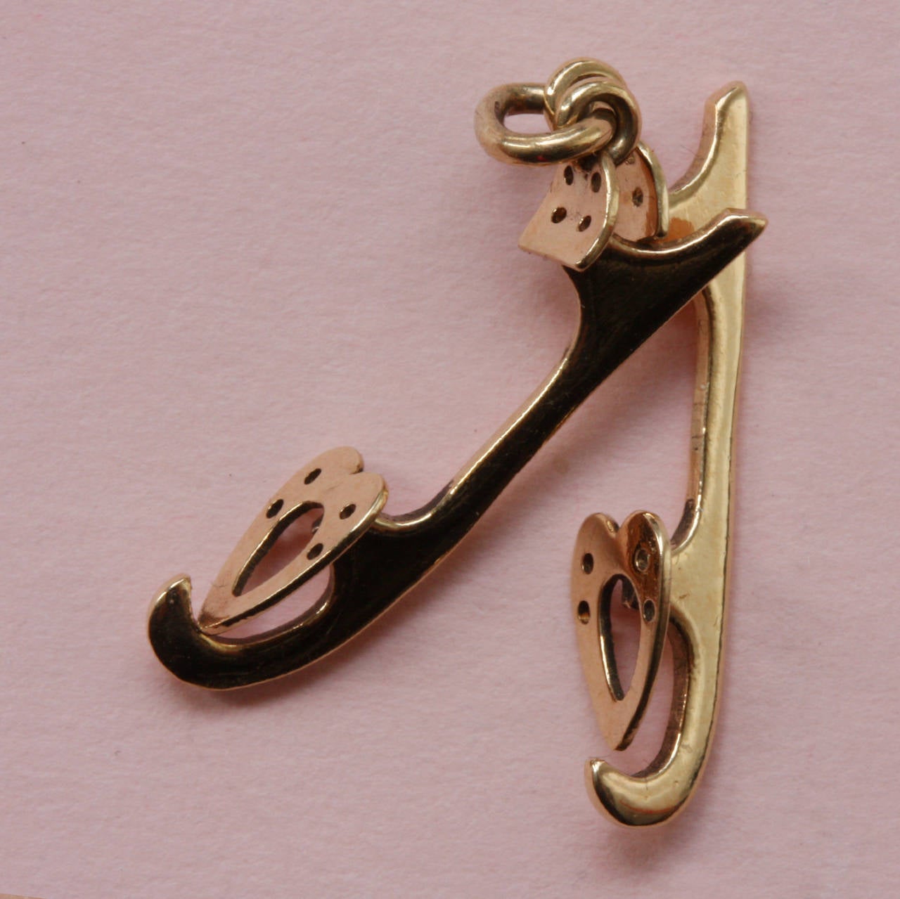 A 14 carat gold love charm of two ice-skates with hearts, each skate is signed: Cartier.

weight: 1.5 grams
length: 2 cm.